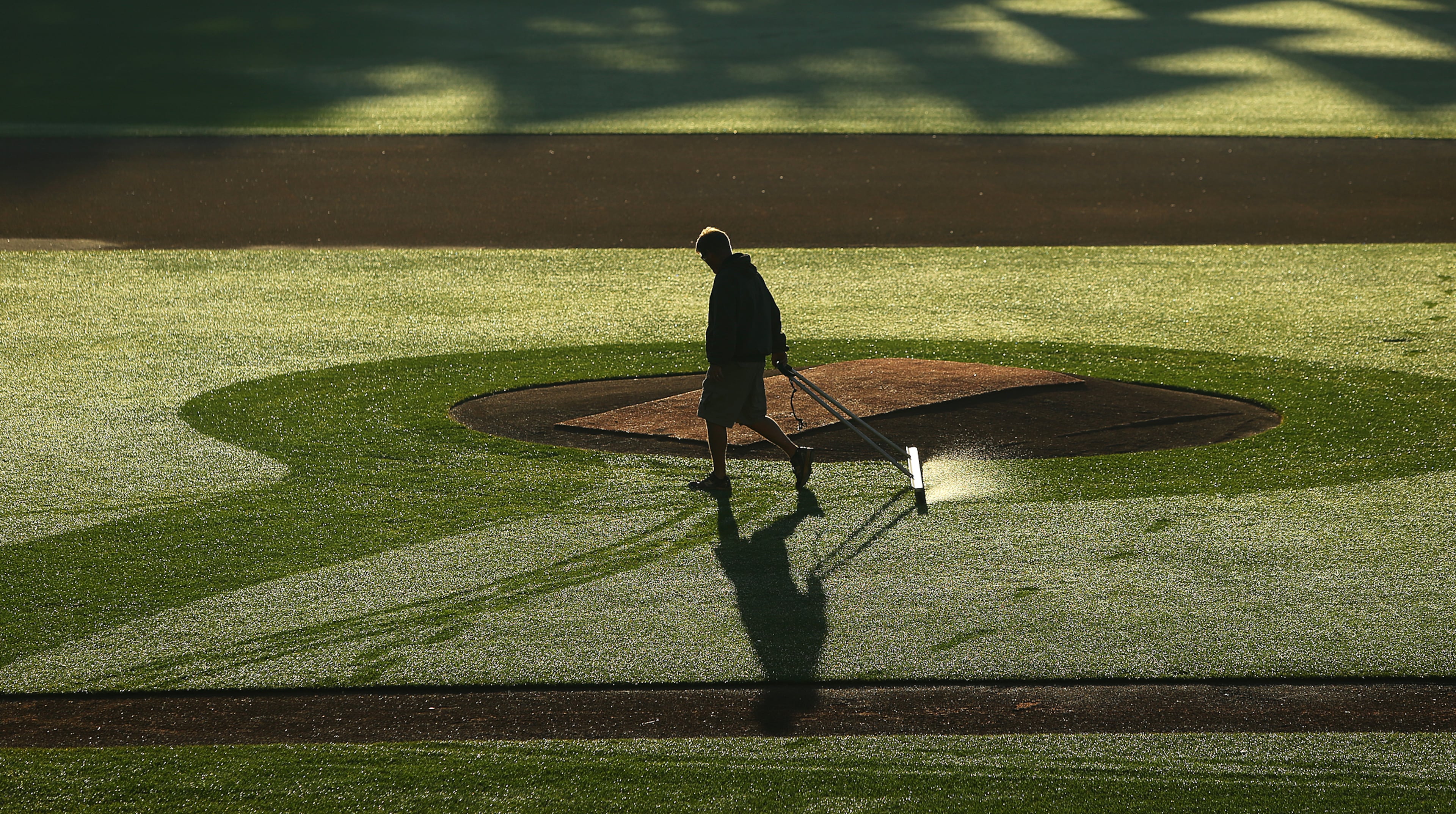 A Braves ground crew member gets the dew off the field in Lake Buena Vista, Fla.