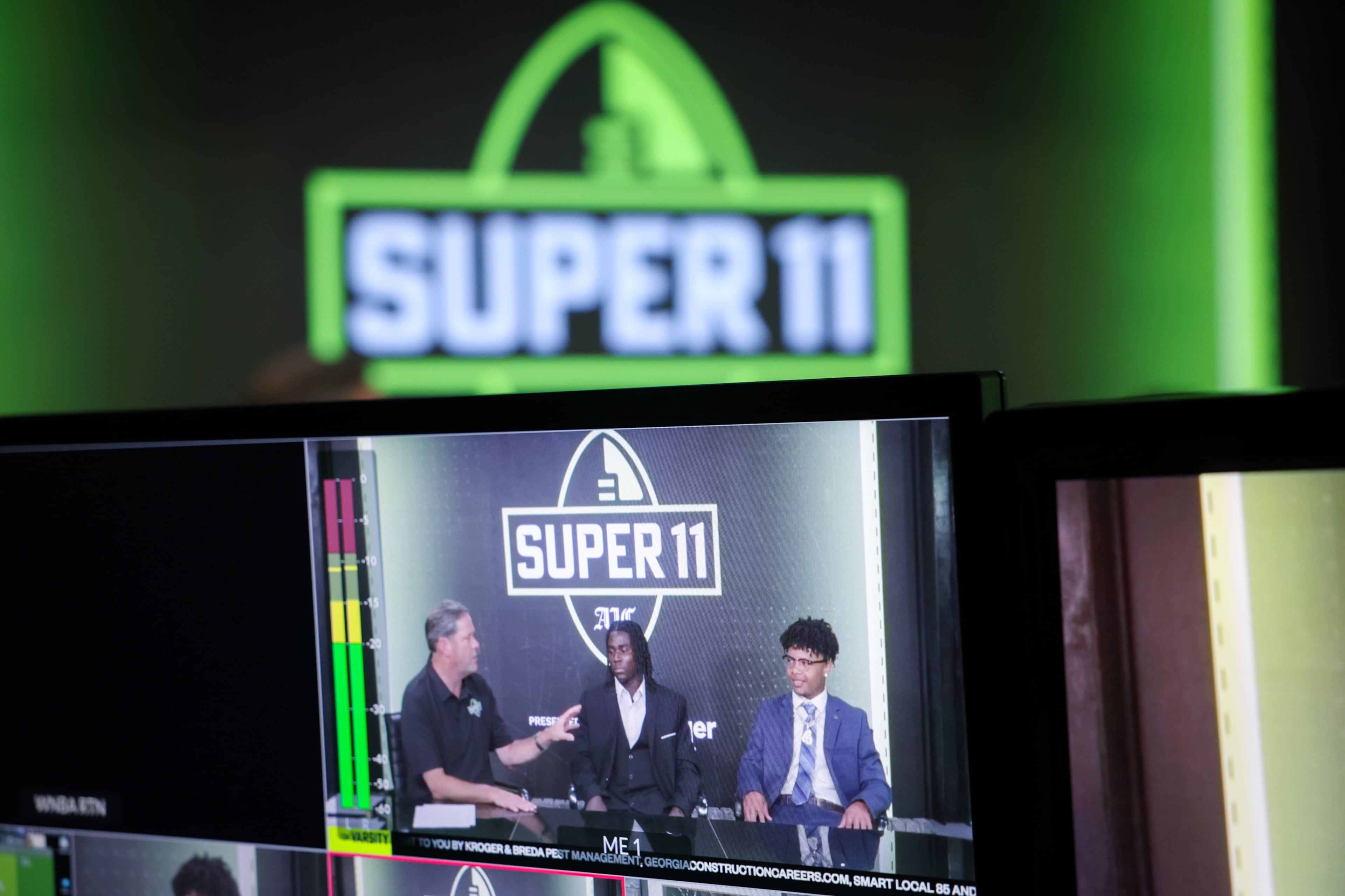 (L-R) DawgNation’s Brandon Adams interviews Creekside’s Gary Walker and Valdosta’s Marquis Fennell during the taping of the Super 11 reveal show at Score ATL in Roswell on Aug. 3, 2026. (Arvin Temkar/AJC)