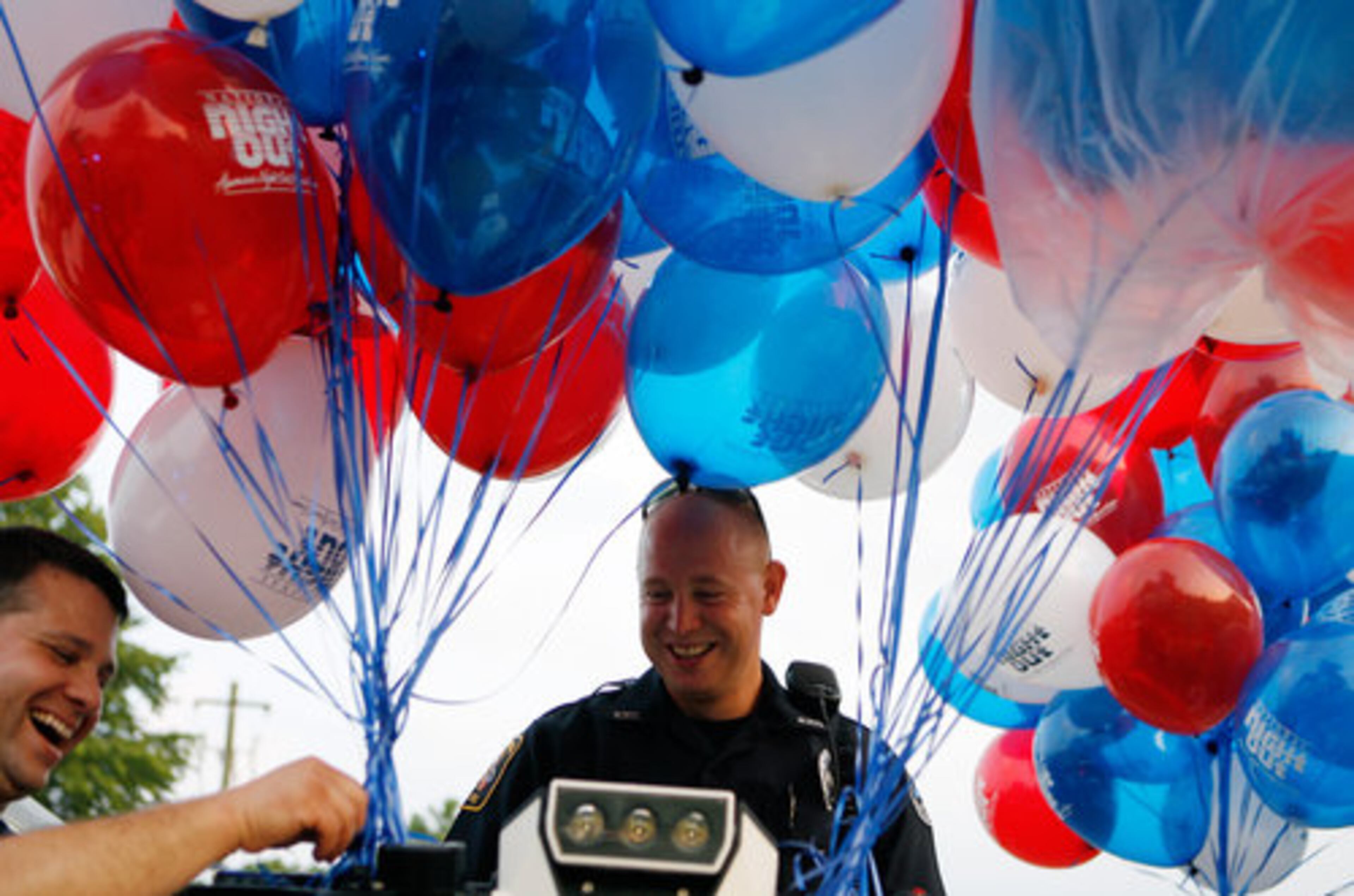 Marietta Police Sgt. P. Bonito (left) ties balloons onto a T3 Series electric standup vehicle before Officer Ben Mixon (center) takes the vehicle to the Casa Mia Trace apartment complex tennis court during the National Night Out event in Marietta on Tuesday, Aug. 3, 2010.