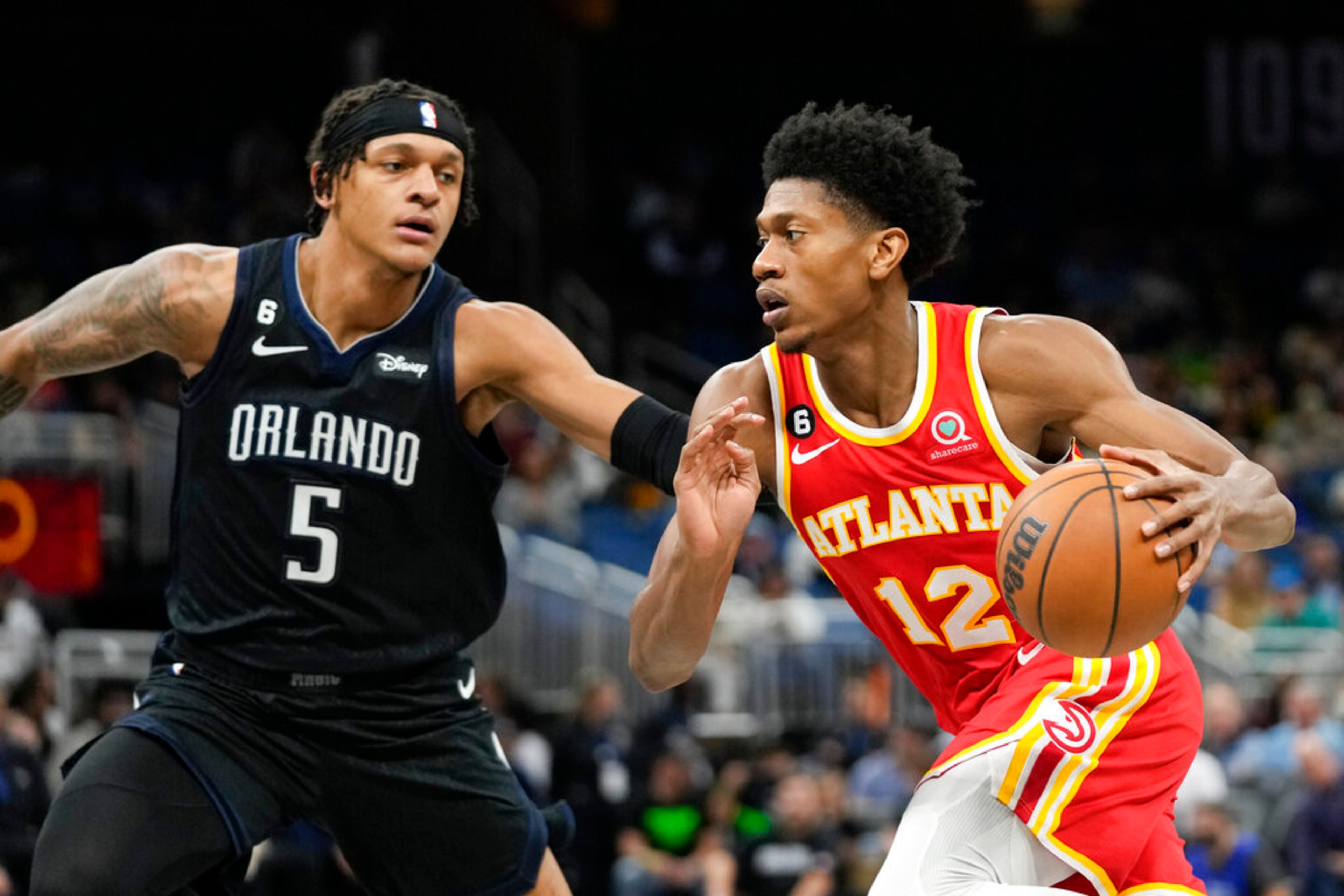 Atlanta Hawks' De'Andre Hunter (12) drives around Orlando Magic's Paolo Banchero (5) during the first half of an NBA basketball game, Wednesday, Dec. 14, 2022, in Orlando, Fla. (AP Photo/John Raoux)