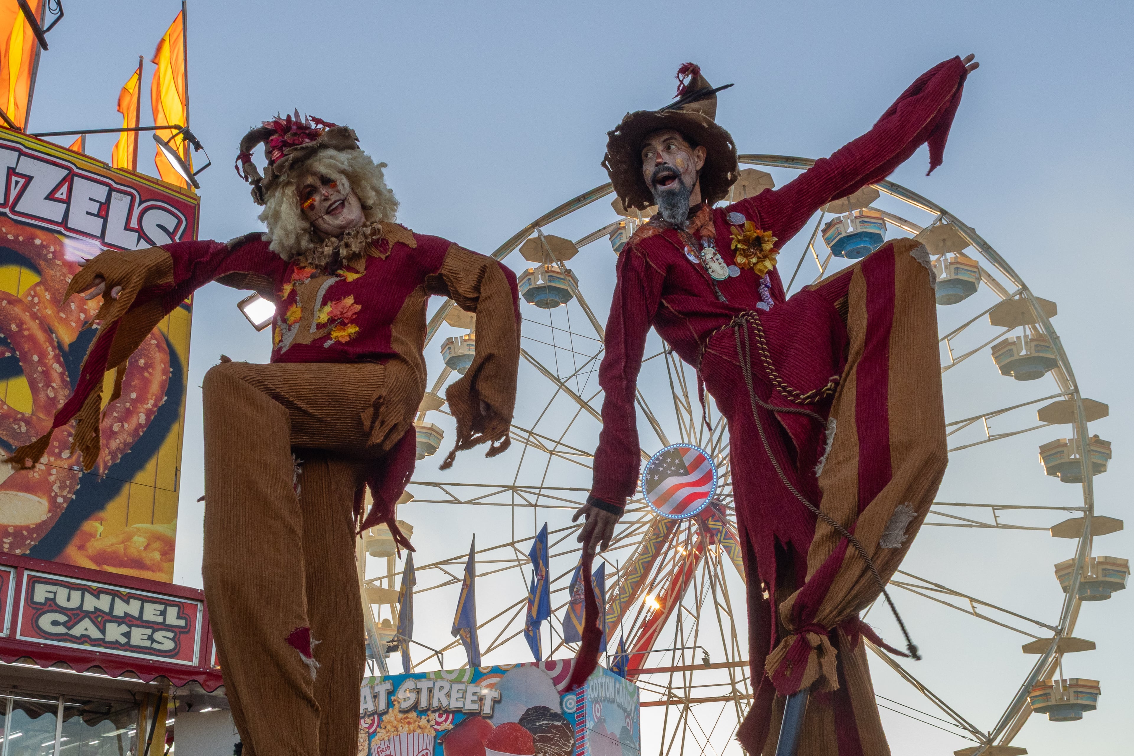 Stilt-walkers Star Child and Richard Dalton of Stilt Circus pose for a photo in front of a Ferris wheel at the 37th annual Georgia National Fair on Saturday, October 17, 2026. The duo are finishing their year-long tour in Georgia after traveling all over the country for different fairs. (Wesley Webb/UGA Photojournalism Workshop)