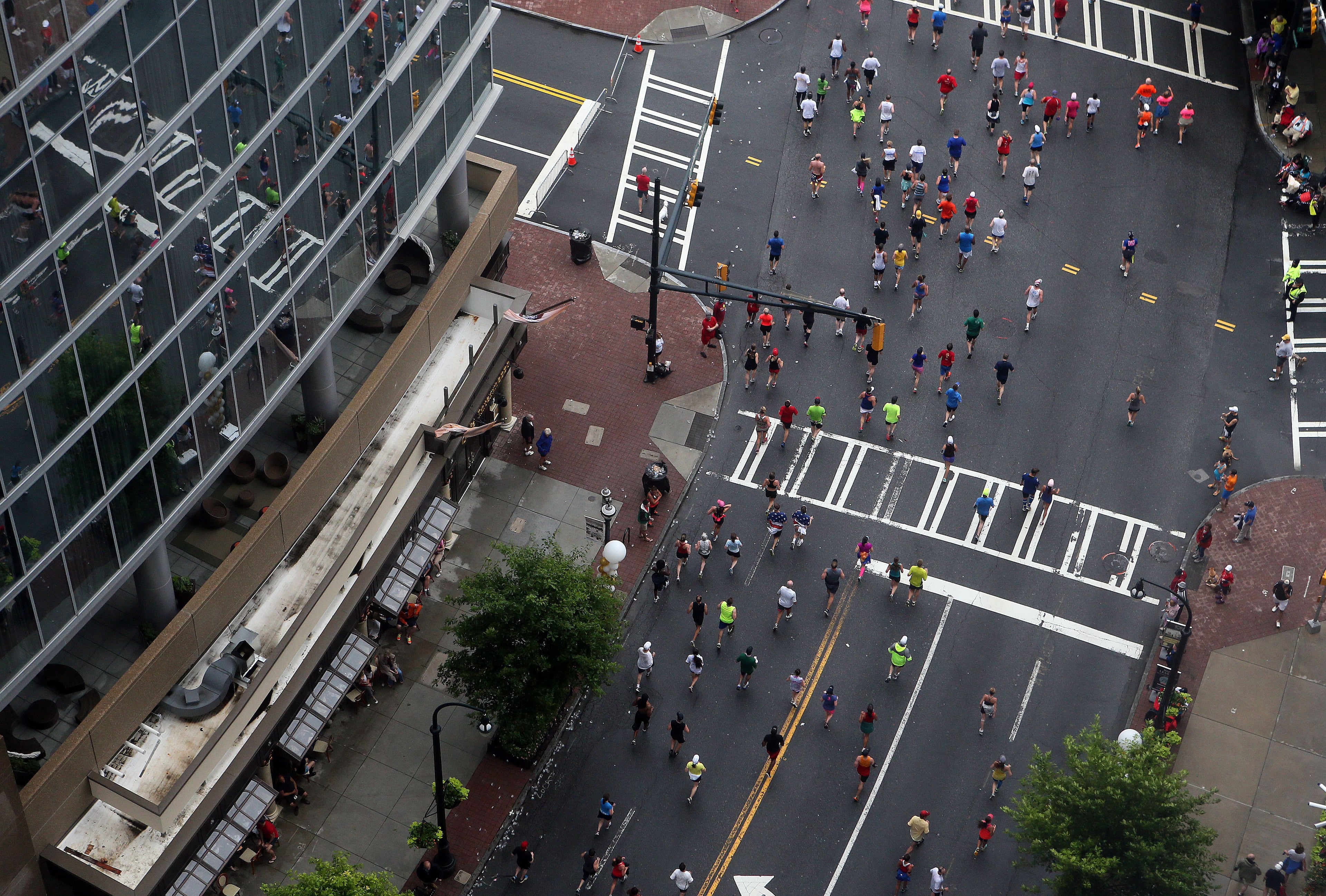 Runners are reflected in a building front in mid-town during 44th running of the AJC Peachtree Road Race in Atlanta on July 4th, 2013. It is the world's largest 10k running event according to the Atlanta Track club who puts it on. PHIL SKINNER / PSKINNER@AJC.COM