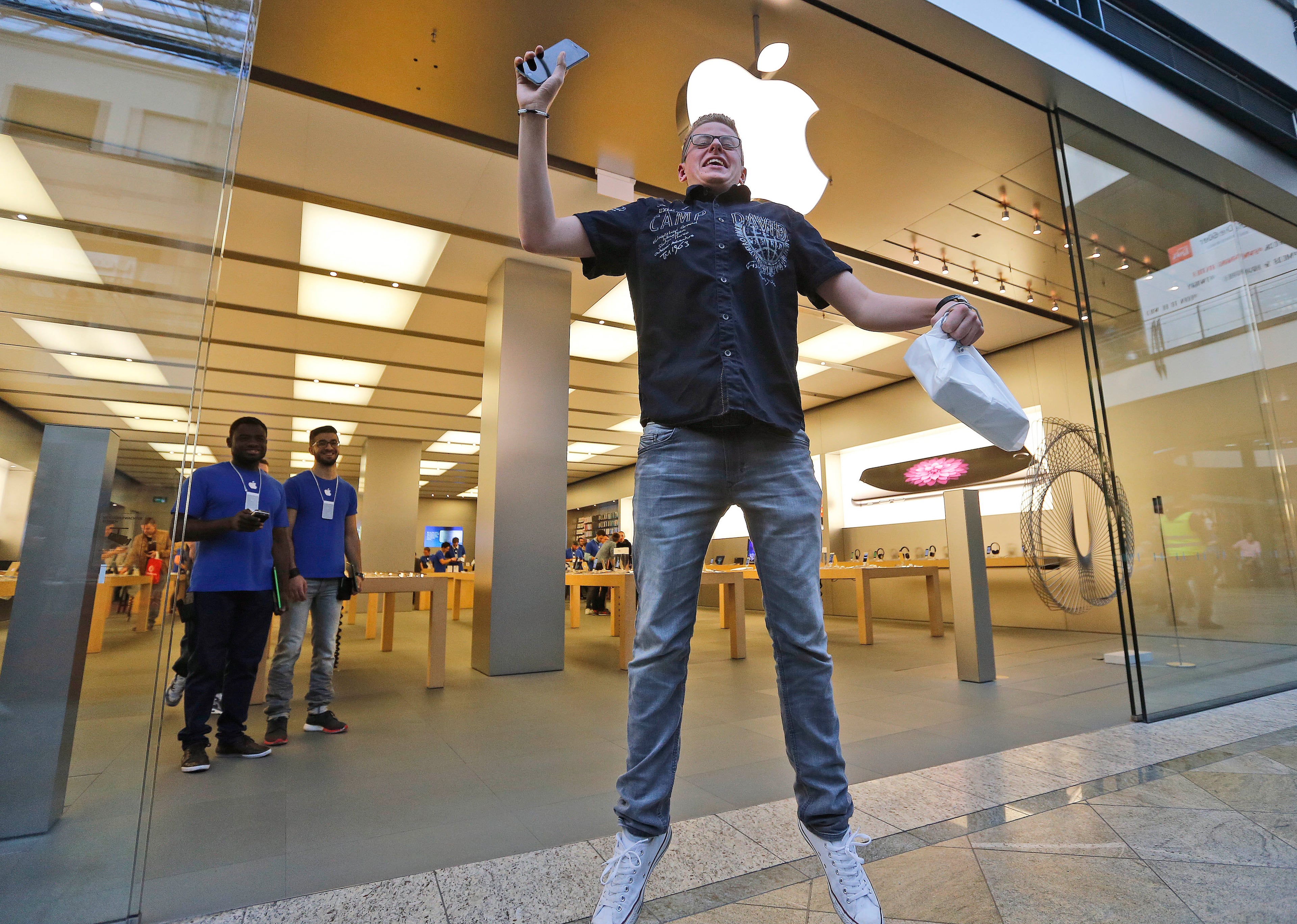 First customer Max, 20, jumps in joy with new mobile phones in his hands during the launch of the Apple iPhone 6 sale at a store in Oberhausen, Germany, Friday, Sept. 19, 2014.(AP Photo/Frank Augstein)