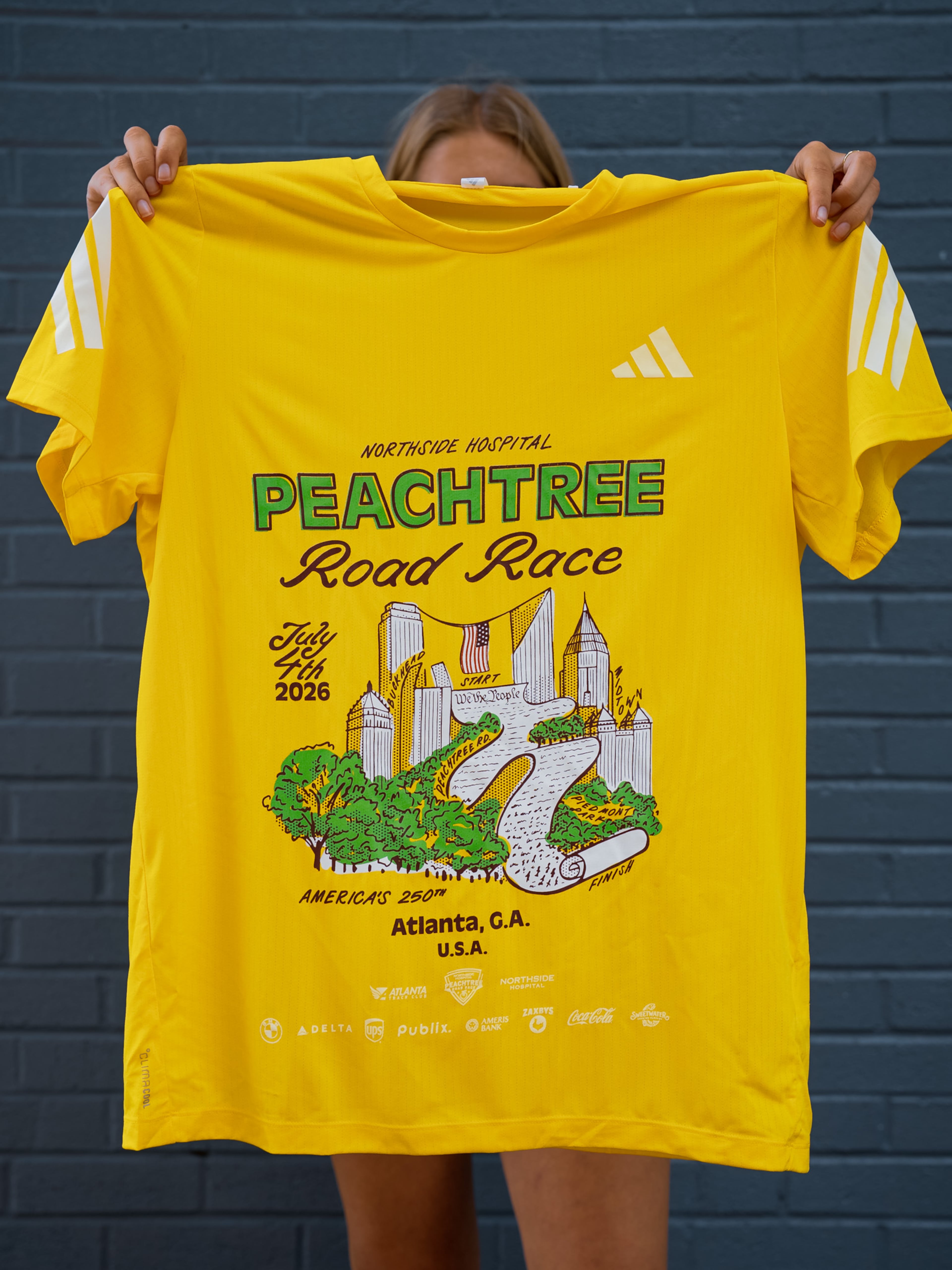The 2026 Peachtree T-shirt design, ‘We the Peaches,’ was created by Dyan Szall. (Courtesy Atlanta Track Club)
