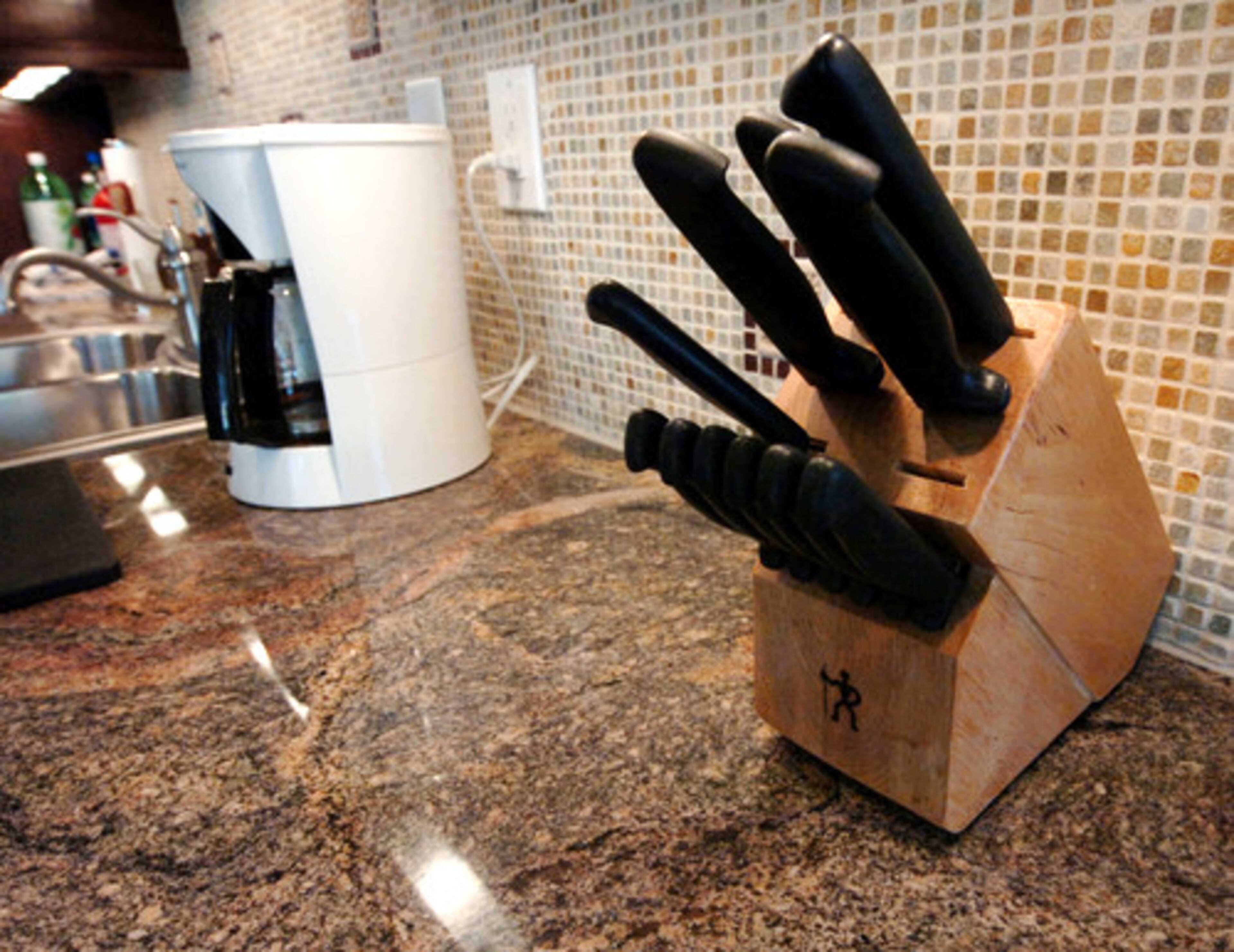 The backsplash on both sides of the kitchen is a mix of large and small decorative tiles.