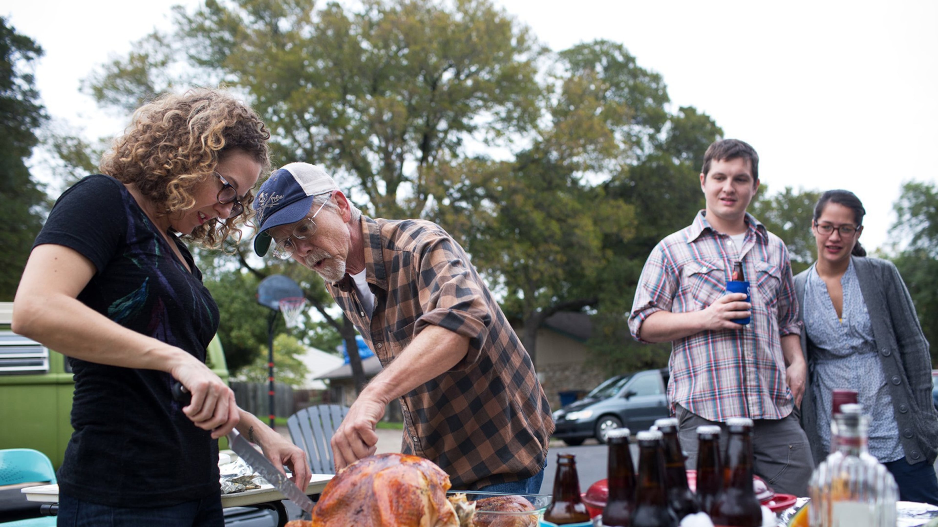 Tim Pankratz helps Addie Broyles carve the turkey she prepared at a Friendsgiving potluck in South Austin.