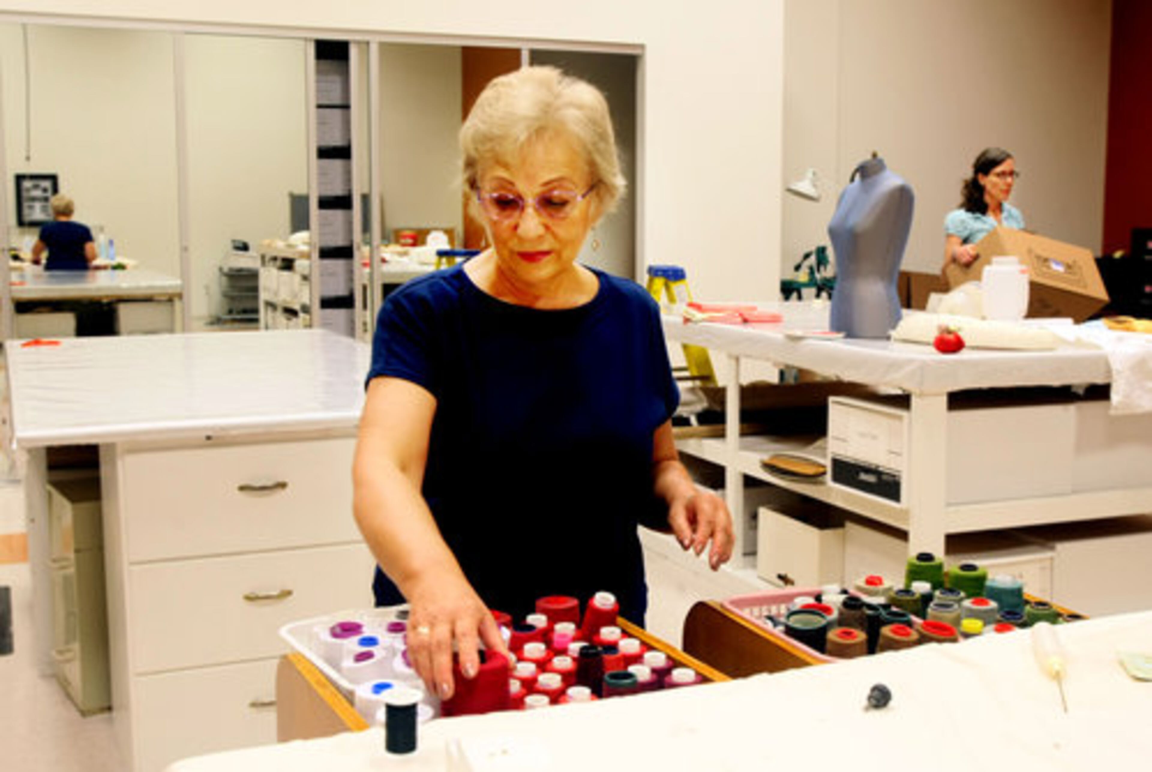 Elena Rao organizes thread spools in the costume shop as Heidi Parikh helps unpack.