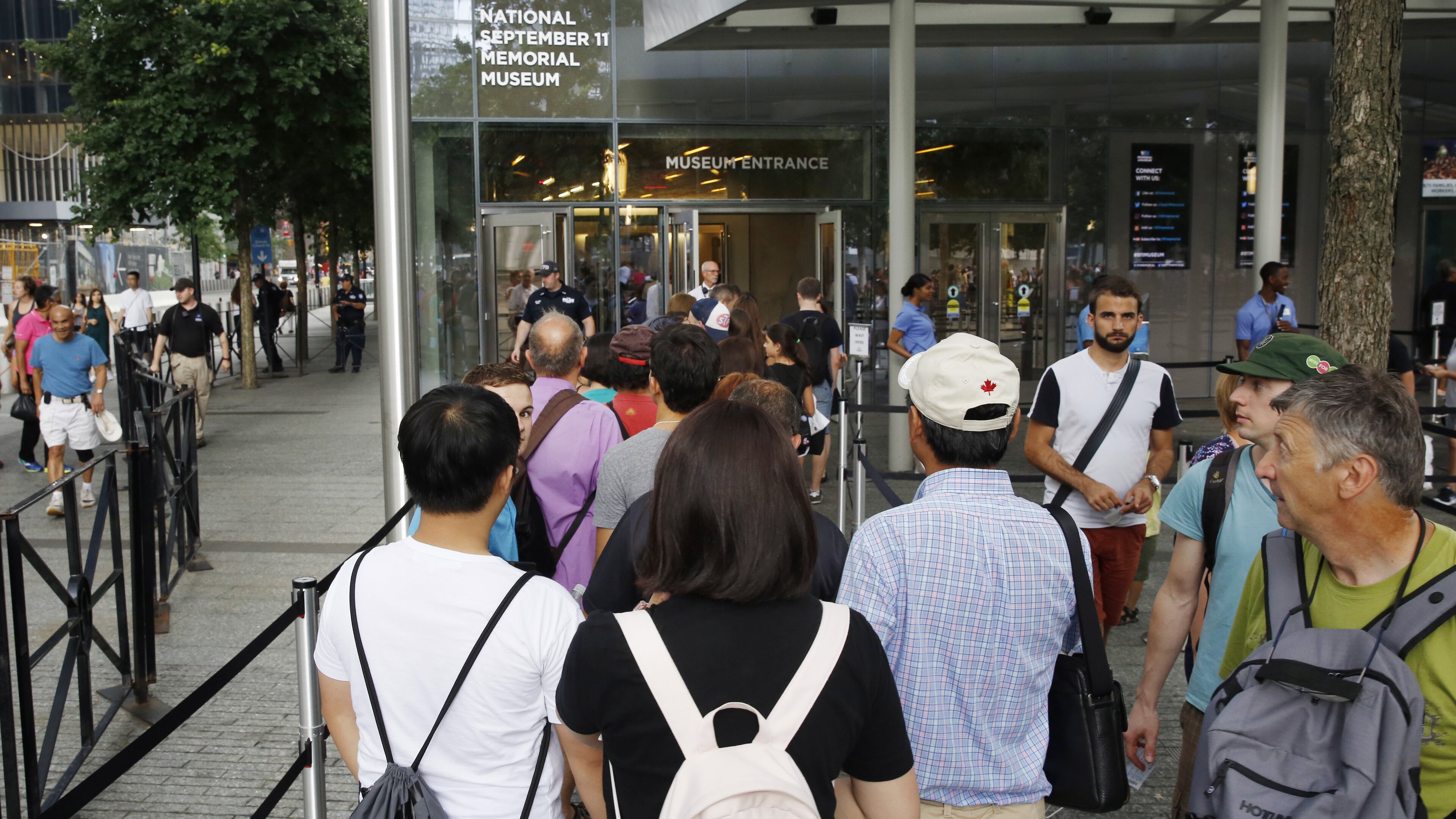 In this July 11, 2017 photo, visitors holding tickets line up at the entrance to the National September 11 Memorial and Museum in New York. Last winter the U.S. tourism industry worried about a "Trump slump," fearing that Trump administration policies might discourage international travelers from visiting the U.S. But statistics from the first half of 2017 suggest that the travel to the U.S. is robust and a number of sectors have reported increased international visitation, with one expert calling it a "Trump bump." The museum is among those reporting more international visitors this year compared to the same period in 2016. (AP Photo/Kathy Willens)