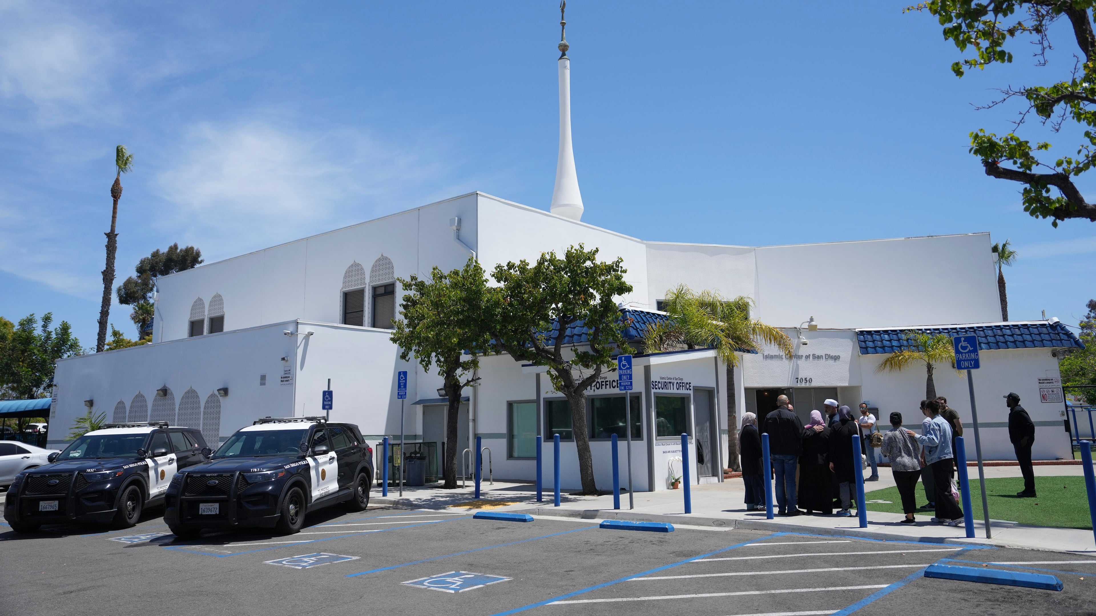 FILE - People gather as police vehicles are parked outside of the Islamic Center of San Diego, the day after a shooting, May 19, 2026, in San Diego. (AP Photo/Jae C. Hong, File)