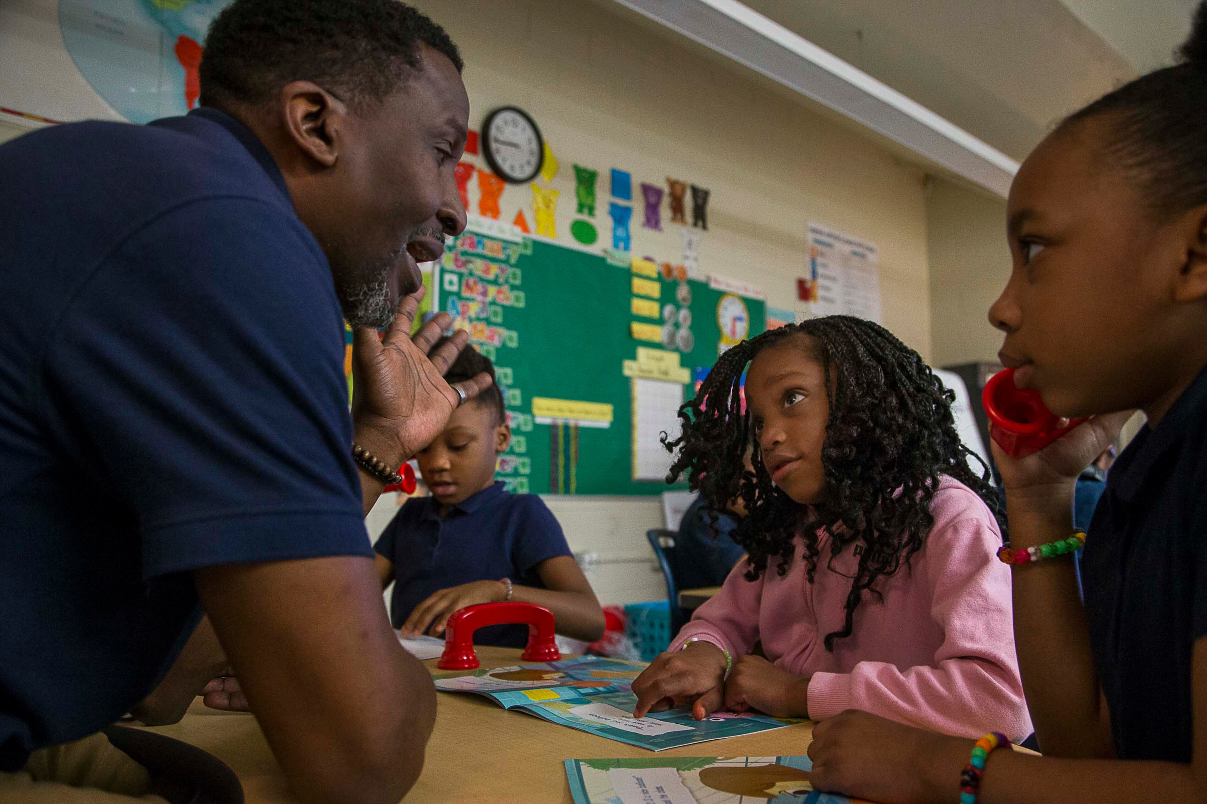 Harper-Archer Elementary School first grader Amiya Watley (second from right) reads aloud to her first grade teacher, Rokeem Pough, (left) during a small group reading exercise on Wednesday, Feb. 26, 2020. (ALYSSA POINTER/ALYSSA.POINTER@AJC.COM)