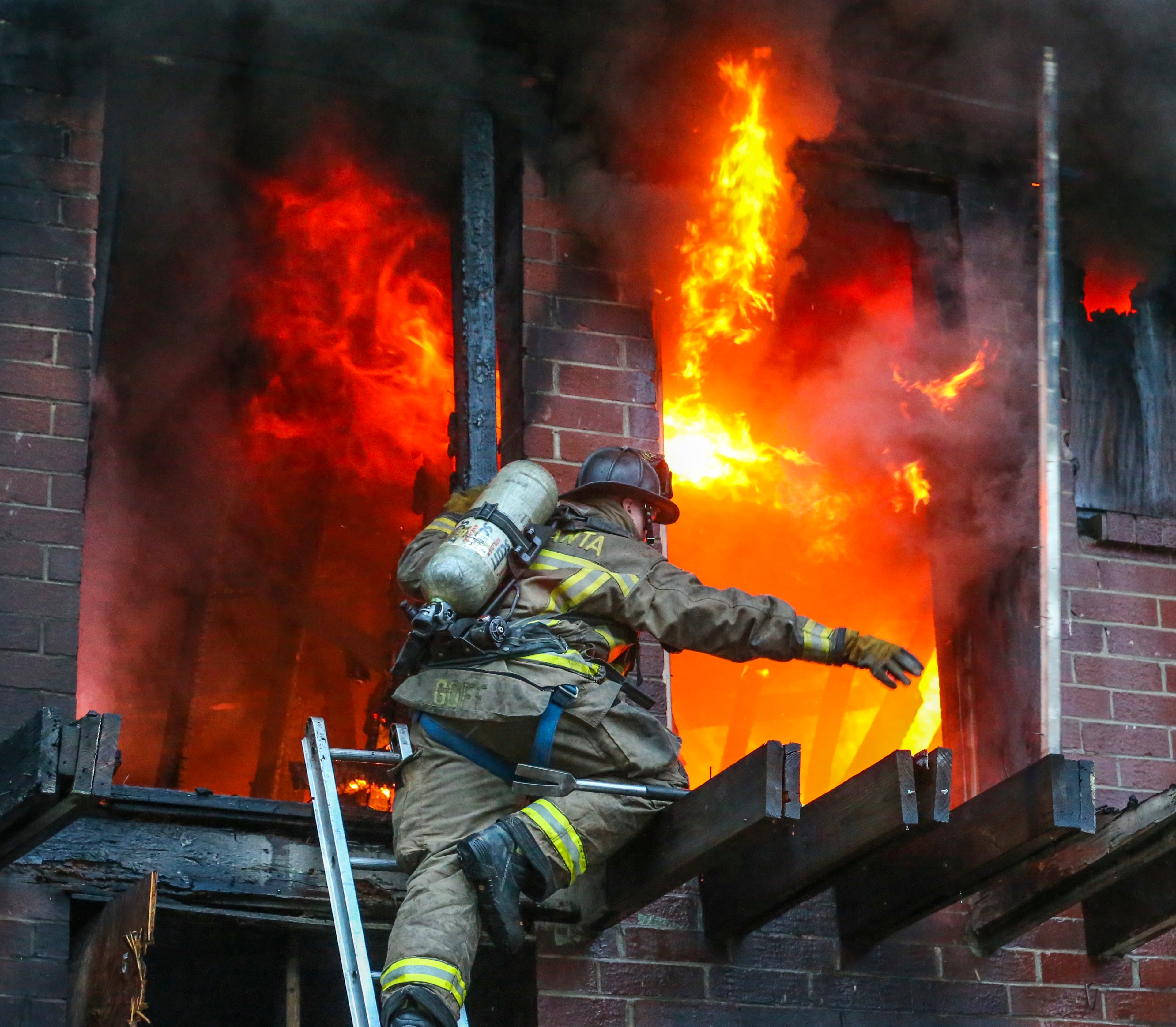 LEDE PHOTO - August 28, 2015 Atlanta: Atlanta firefighter, Matt Goff of Squad 4 works on removing boards so crews can get water on the fire. Atlanta firefighters battled an apartment blaze just south of I-20 near downtown Friday morning, Aug. 28, 2015. The fire was reported about 7 a.m. in a two-story, brick apartment building in the 400 block of Rawson Street, between McDaniel and Windsor streets. Atlanta fire spokeswoman Janet Ward said the building is vacant, and no injuries were reported. The flames could be seen from I-20 at 7:30 a.m., and smoke was drifting over the interstate. Battalion Chief , Richard Heard said arriving units encountered heavy fire conditions and had to go defensive but resumed offensive operations and then concluded searches to make sure everyone was accounted for. "Early on it was quite challenging for us once we got enough personnel on the scene we were able to conduct a thorough assessment and put our resources where they needed to be," Heard said. JOHN SPINK / JSPINK@AJC.COM