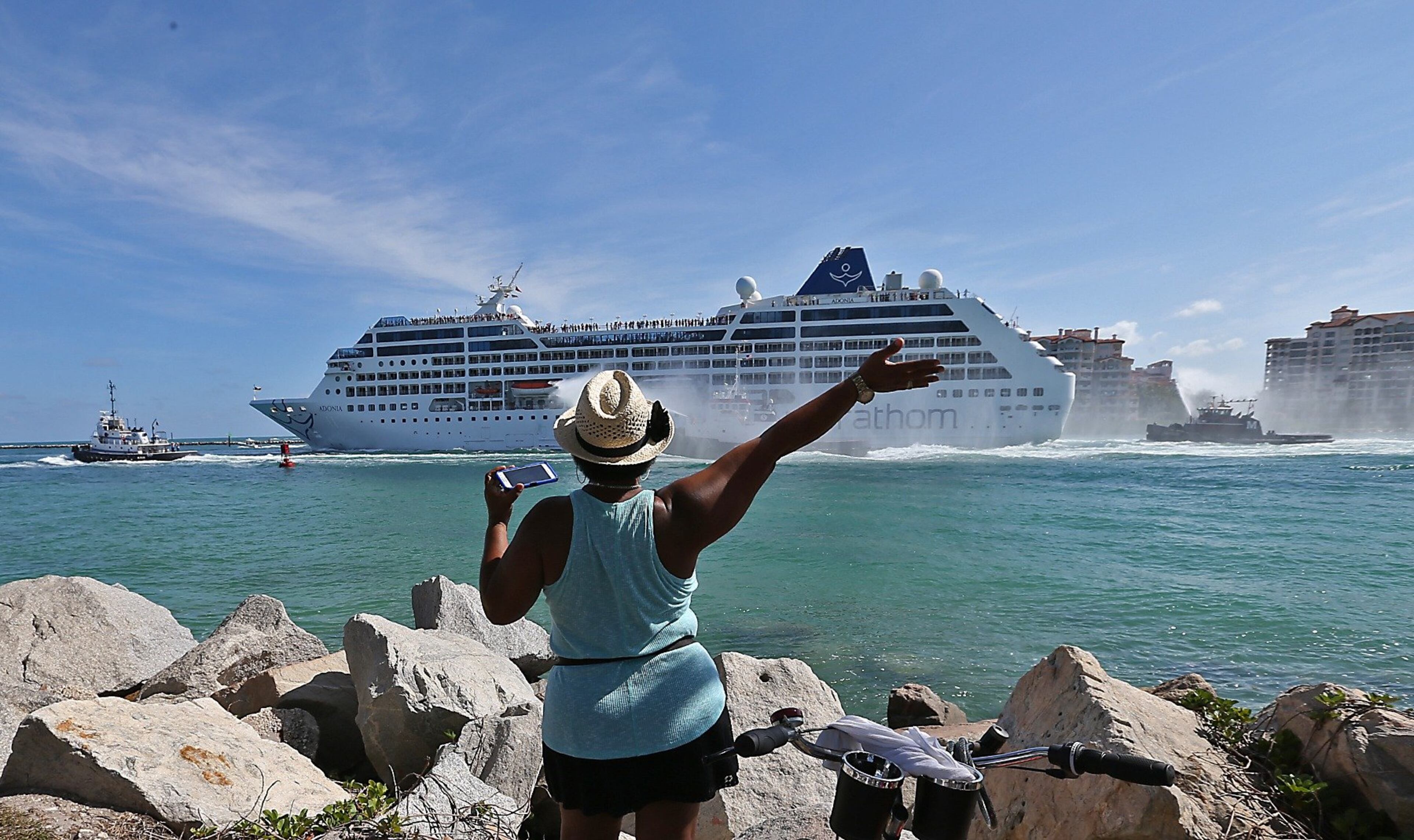 A woman from Cuba waves Adonia leaves port in Miami, Sunday, May 1, 2016, en route to Cuba. After a half-century of waiting, passengers finally set sail on Sunday from Miami on an historic cruise to Cuba. Carnival's Cuba cruises, operating under its Fathom band, will visit the ports of Havana, Cienfuegos and Santiago de Cuba. (Patrick Farrell/The Miami Herald via AP)
