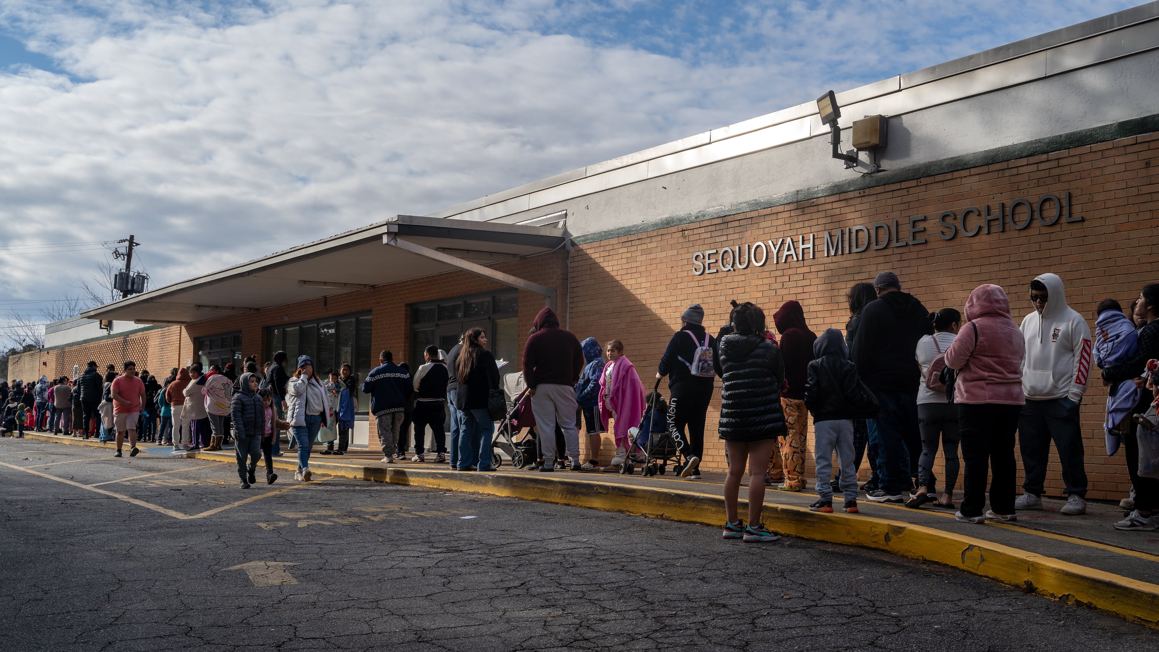 About 300 families line up outside Sequoyah Middle School to receive free food, clothes and COVID vaccines at a "holiday healing" event hosted by local non-profit WeLoveBufordHighway. Saturday, December 14, 2024 (Ben Hendren for the Atlanta Journal-Constitution)