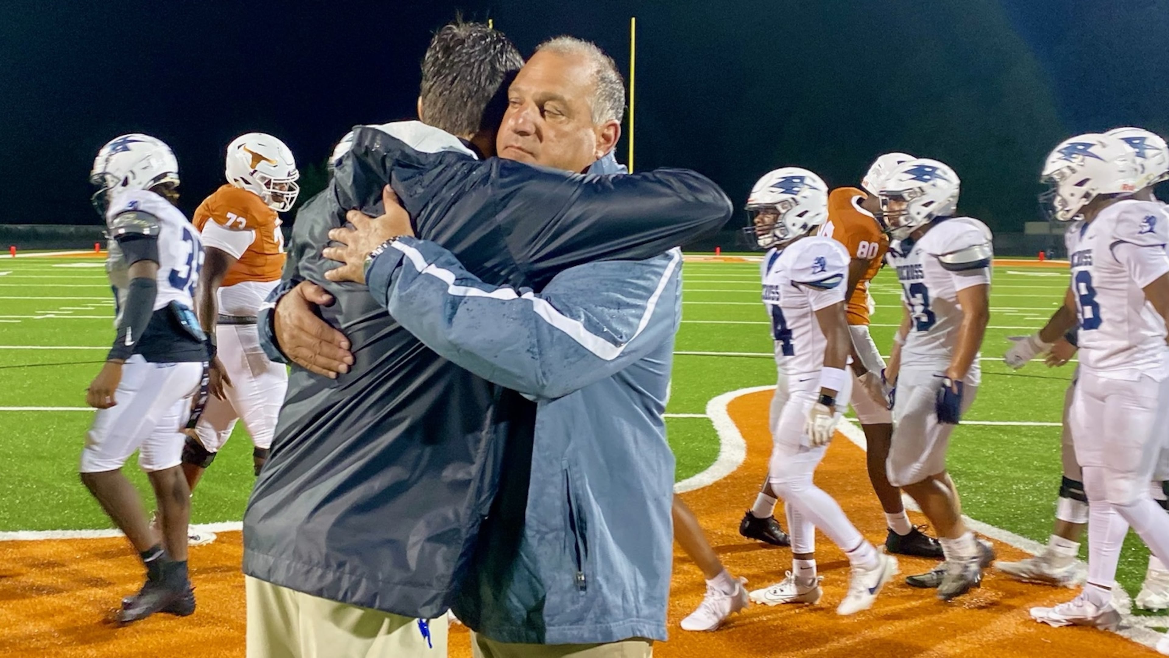 Norcross High coach Keith Maloof hugs his son Tyler Maloof, the coach at Lanier High, after the Blue Devils’ 31-10 win on Friday, Aug. 16, 2024. It was the first father-son coaching matchup in GHSA football since 2006. (Ken Sugiura/AJC 2024)