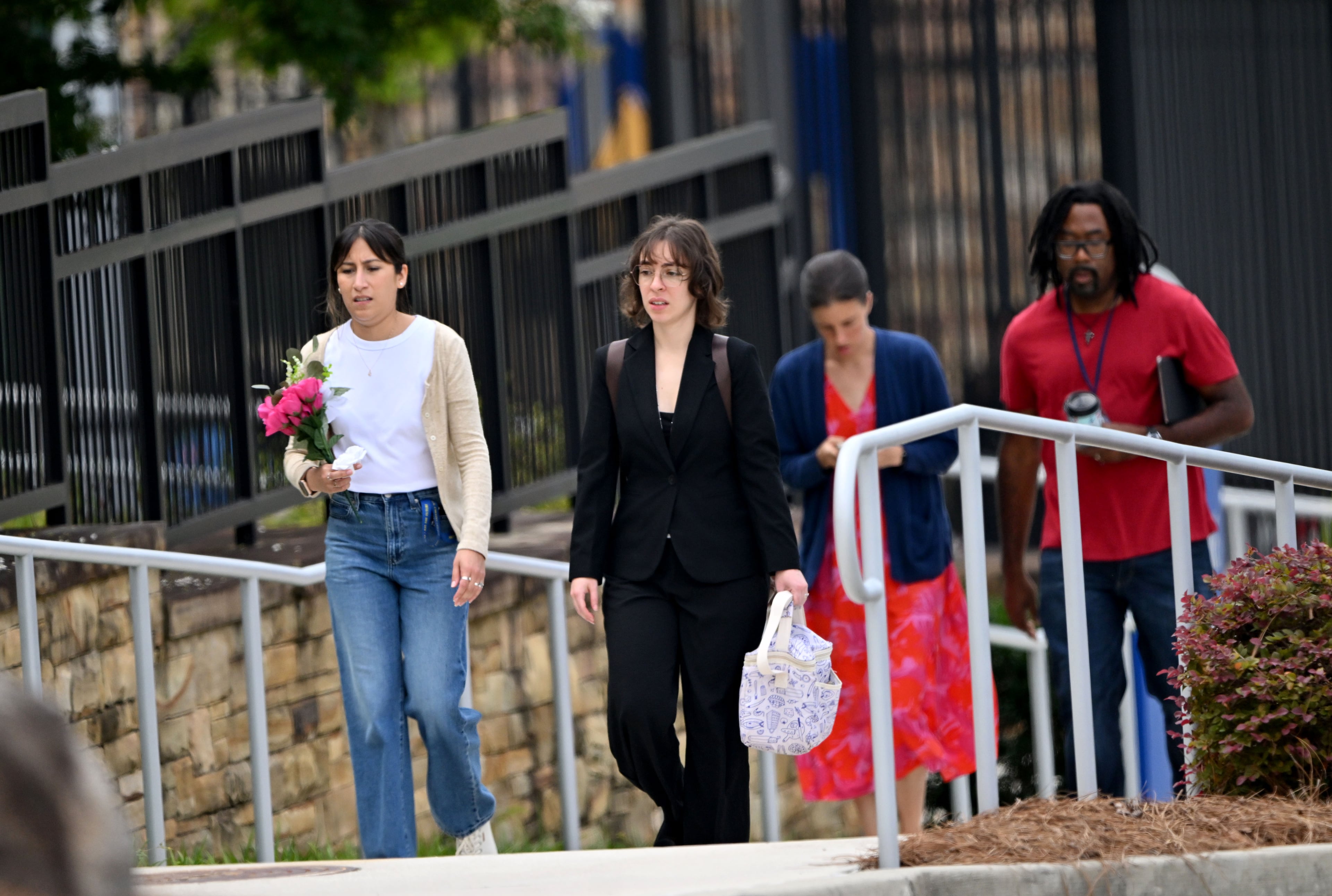 CDC employees, including a woman holding flowers, visit a memorial honoring Officer David Rose outside CDC headquarters on Friday, Aug. 7, 2026. (Hyosub Shin/AJC)
