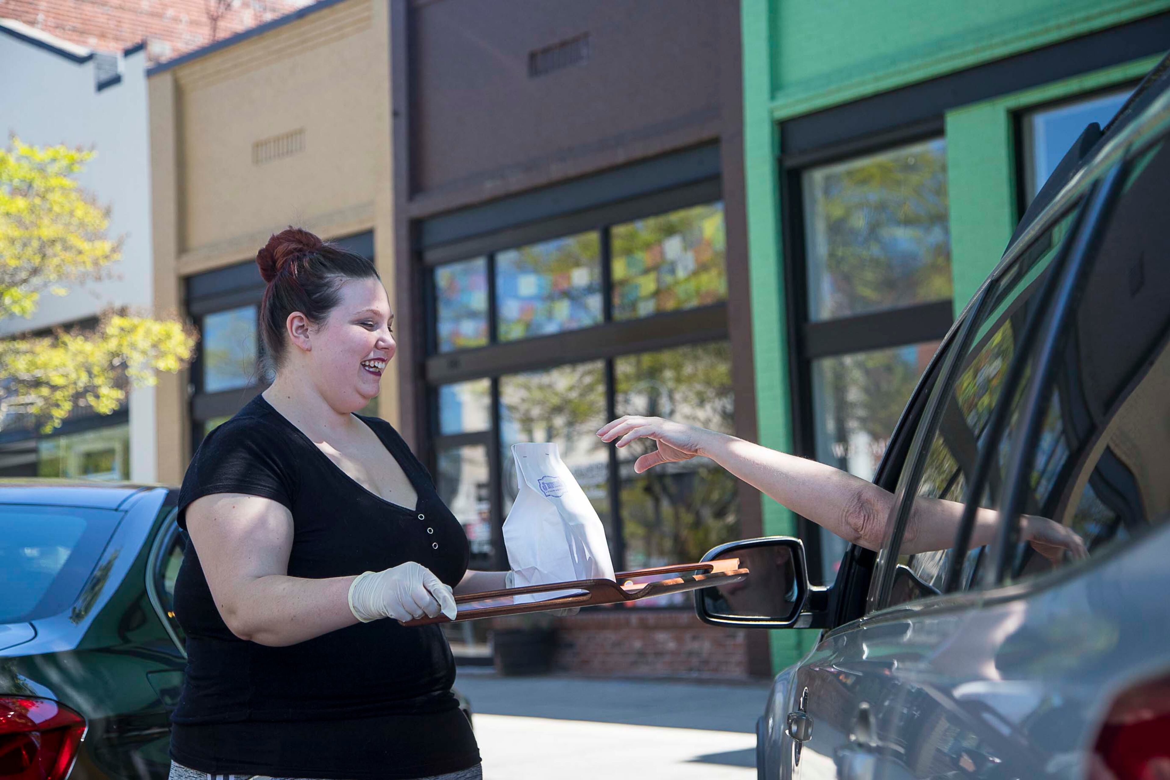 04/03/2020 - Rome, Georgia - Jamwich restaurant sever Elizabeth Spruell delivers a customers meal to their car in historic downtown Rome, Friday, April 3, 2020. Jamwich has been preparing curbside pick-up orders for about three weeks, Spruell said. Elizabeth went from working six days a week to only a couple days at the restaurant. (ALYSSA POINTER / ALYSSA.POINTER@AJC.COM)