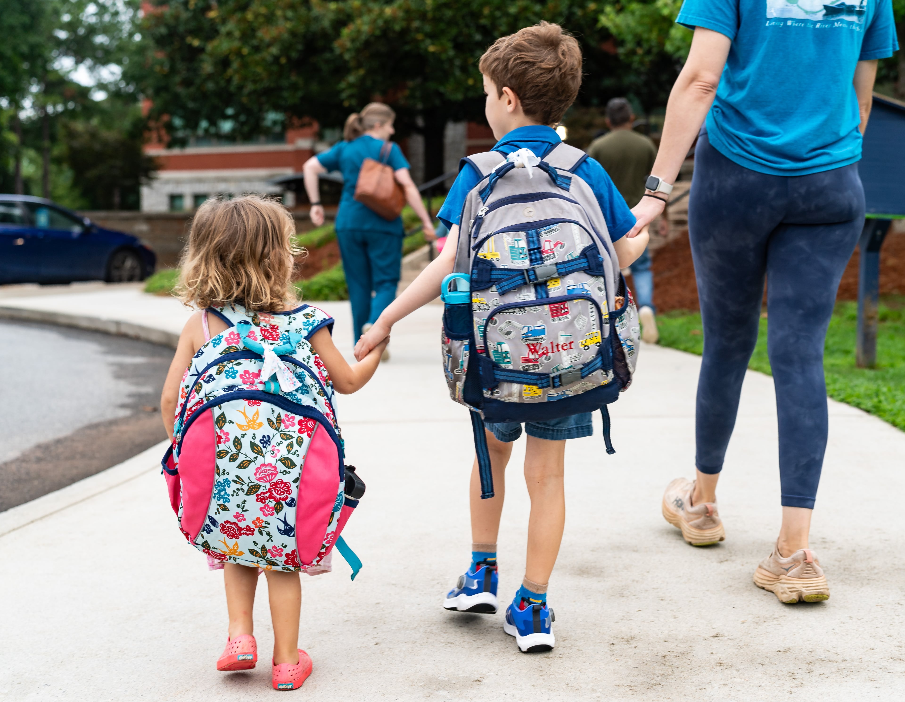 Walter Andreason, 5, walks with his sister Phoebe Andreason and mother Lauren Andreason before his first day of first grade at Glennwood Elementary School in Decatur on Tuesday, July 30, 2024. (Seeger Gray / AJC)