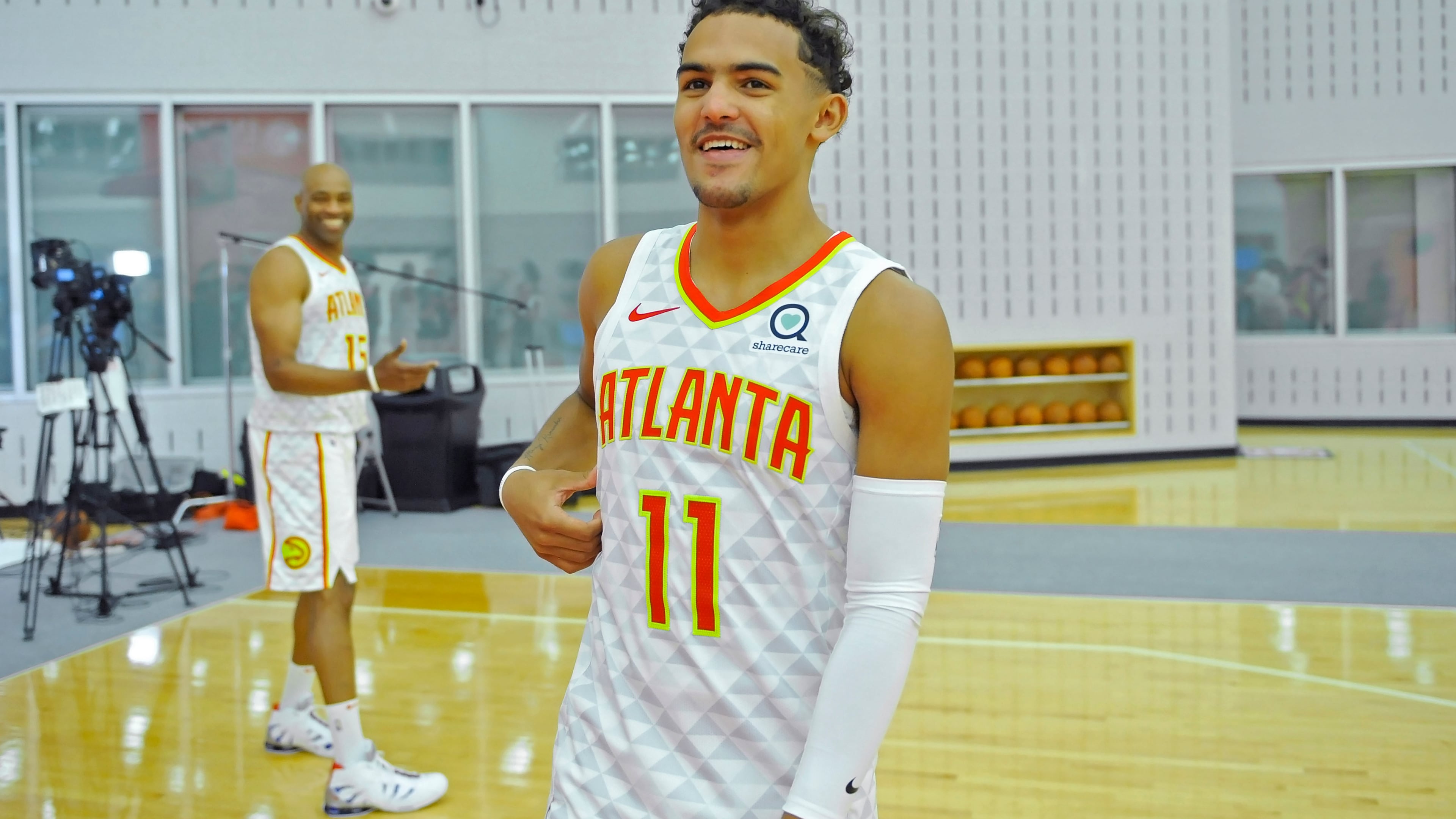 Hawks guard Trae Young smiles as he walks toward reporters after talking with forward Vince Carter (left) during the Atlanta Hawks Media Day Sept. 30, 2019, at Emory Sports Medicine Complex in Atlanta.