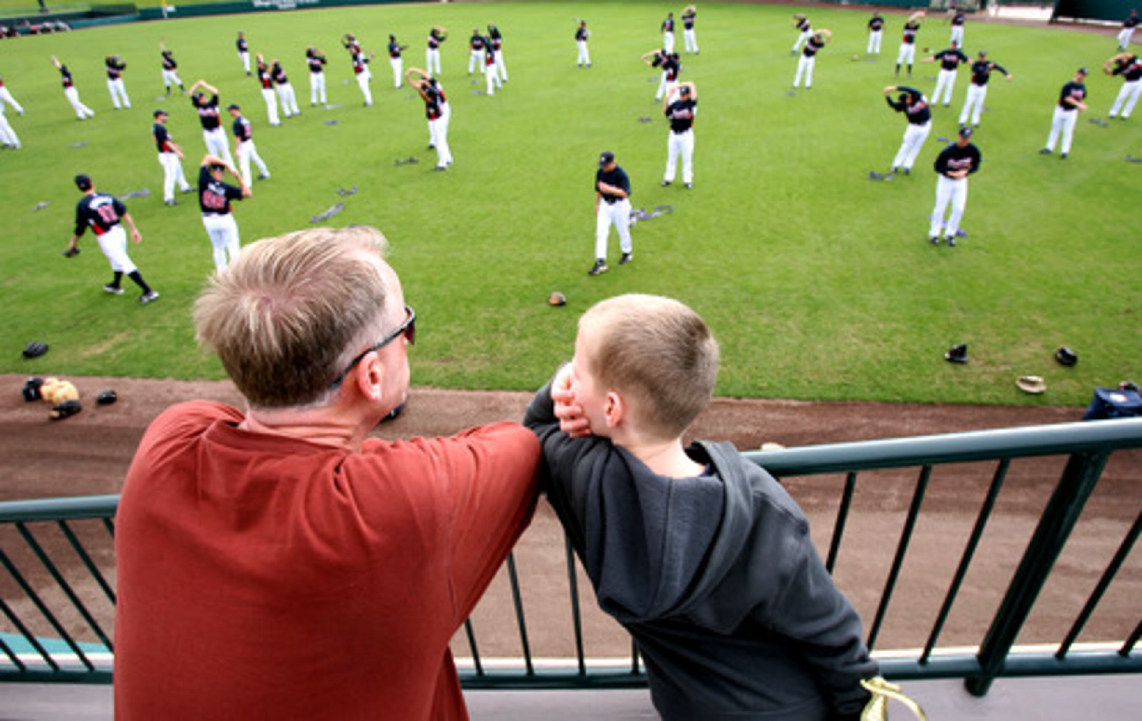 Arnie Ruter and his son Caleb, 6, of Grand Rapids, Mich., watch players go through workouts during the first day of first full squad practice. Ruter said they visited Disney and Magic Kingdom and this is their first time to the ballpark.