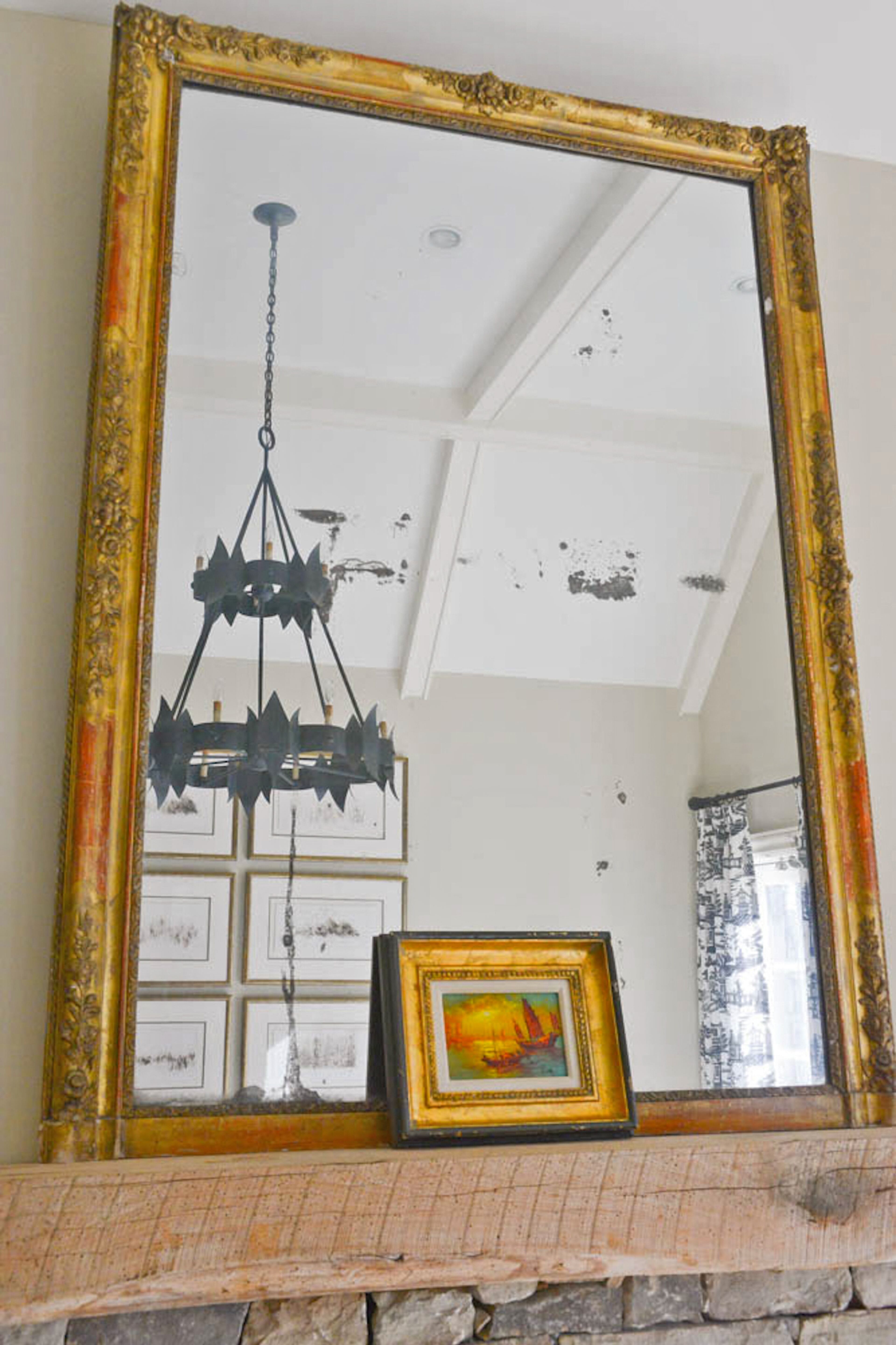 An antique French mirror above the family room fireplace reflects the room's vaulted ceiling and the iron chandelier from Scott Antique Market, two features that Buckhead homeowner Jeanmarie Quarterman loves.