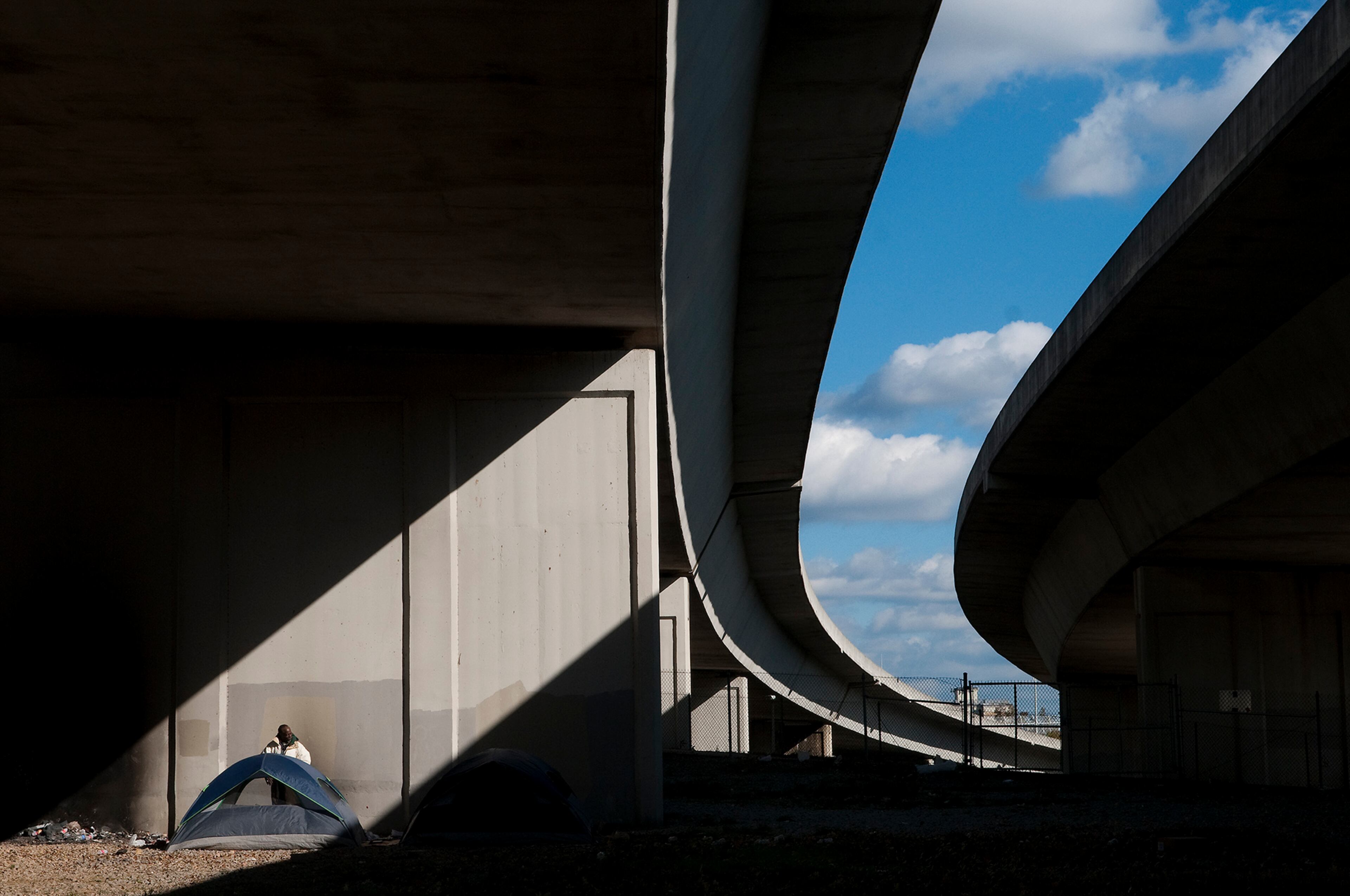 This image by Joeff Davis is part of the "Profiles of Poverty" exhibit. Davis explains: "Rarely do all the elements of a photograph - subject, light, color, emotion - come together in a single 1/60th of a second. This was one of those rare moments. Thomas Wheatley and I spent an intense week interviewing and photographing people who live under the highway for a cover story on homelessness. As we walked away from interviewing "Skipper," a homeless former airport cargo worker, I turned and I saw this." Photographed OCTOBER 29, 2012, 2:47 P.M., UNDERNEATH INTERSTATE 20, I75/85 INTERCHANGE "Skipper," a former airport cargo worker, said his criminal record has made finding a job difficult. Every day more than 300,000 cars travel on the downtown connector and the massive I-20 interchange, where three of the country's busiest interstates converge in the shadow of the state Capitol. The knot of concrete bridges and underpasses designed to streamline high-speed car travel is an engineering marvel - an architectural feat that, ironically, you can't really appreciate until you step out of your car. But in addition to moving cars along, the ramps and bridges also create gaps, nooks, and crannies that have become shelter for homeless men and women. They flock to the state-owned area and ignore the "no trespassing" signs because it's near downtown, where many of the city's homeless service providers are located.