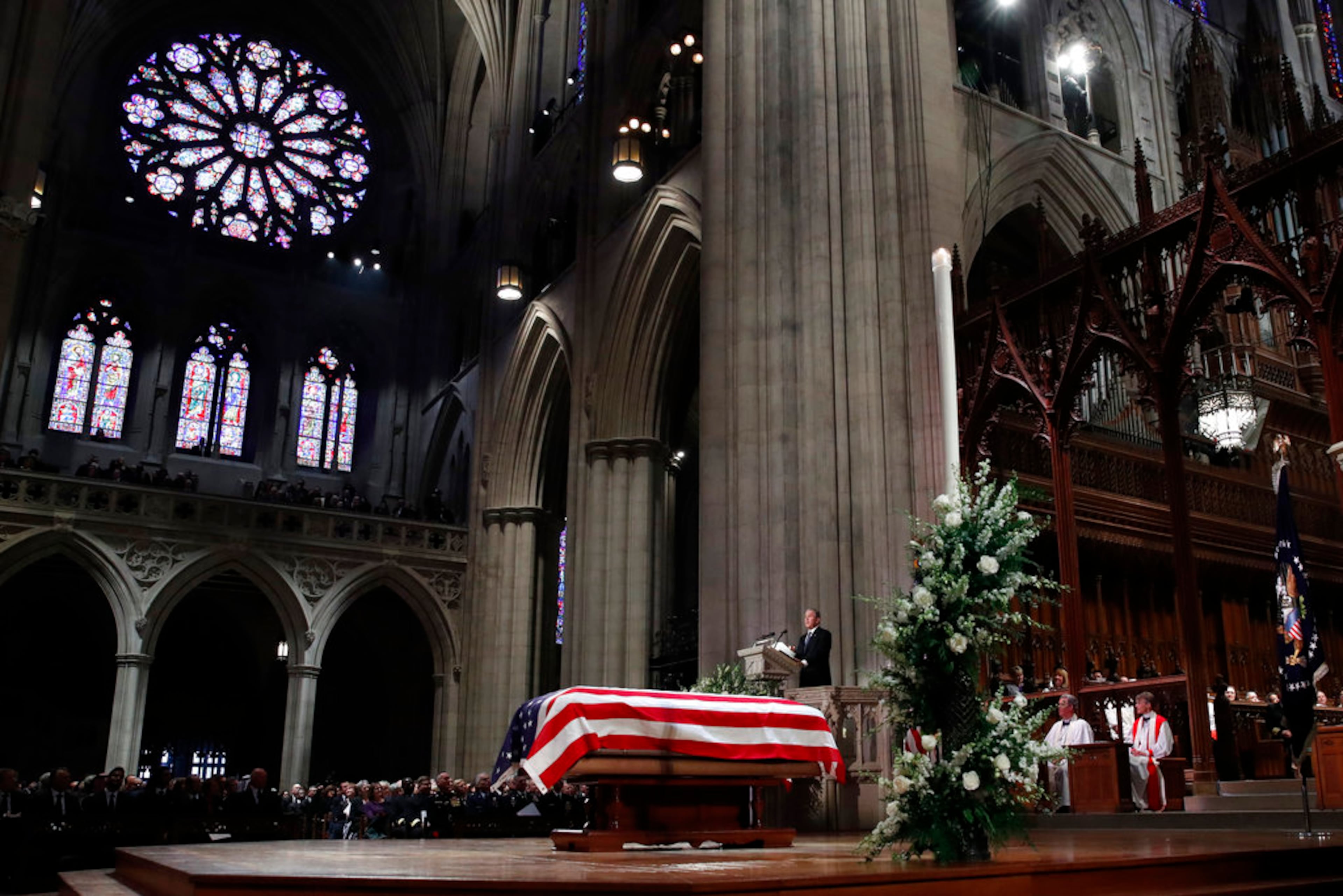 Former President George W. Bush speaks in front of the flag-draped casket of his father, former President George H.W. Bush, at the State Funeral at the National Cathedral, Wednesday, Dec. 5, 2018, in Washington. (AP Photo/Alex Brandon, Pool)