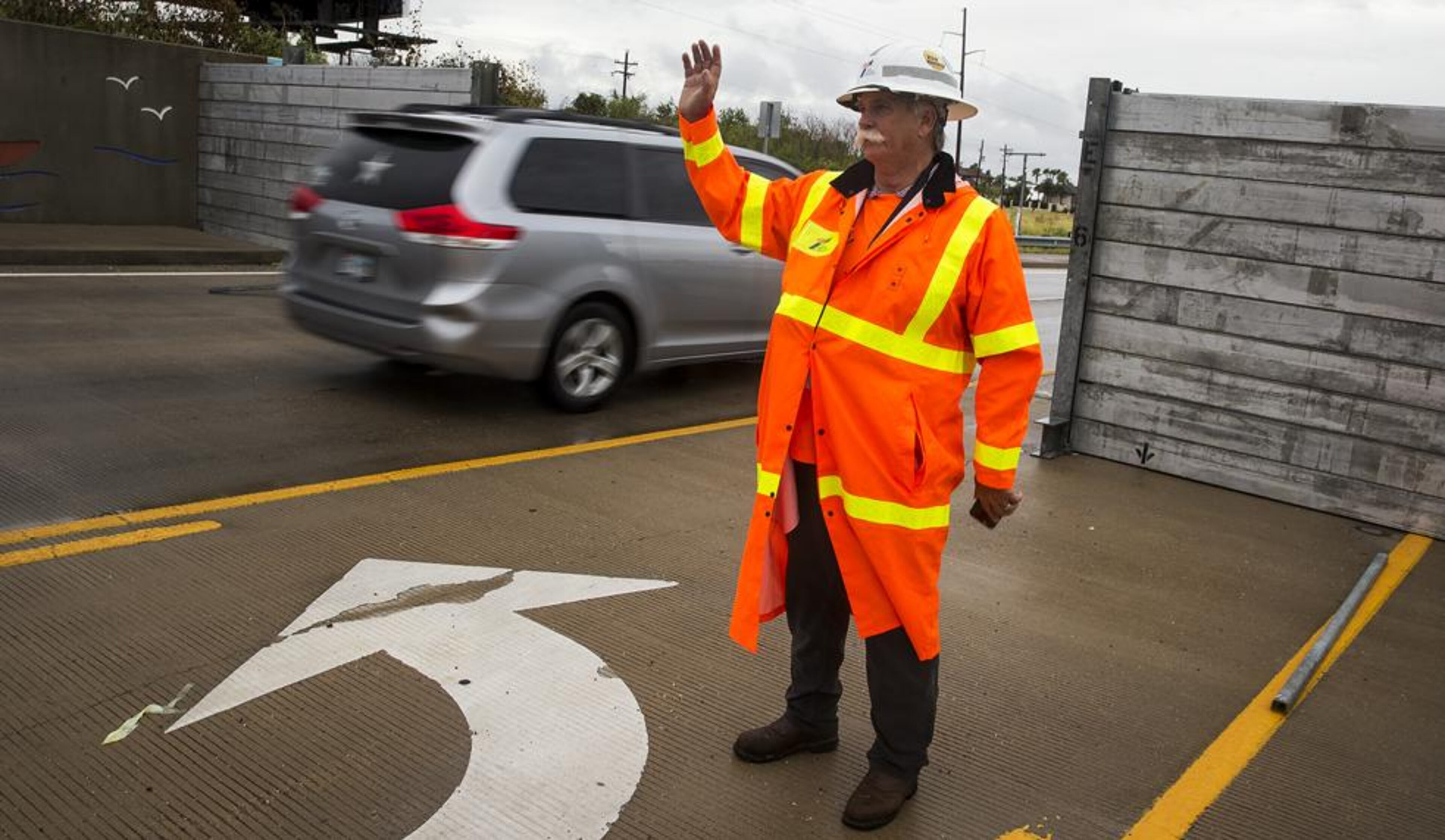 Nick Wagner/AMERICAN-STATESMANRickey Dailey, a public information officer with TxDOT, waves to passing cars as they pass through a surge wall on TX-361 leading to the Port Aransas ferry in Aransas Pass, Texas, on Friday, August 25, 2017. Hurricane Harvey is expected to make landfall on the Texas coast tonight or early Saturday morning as a category 3 hurricane.