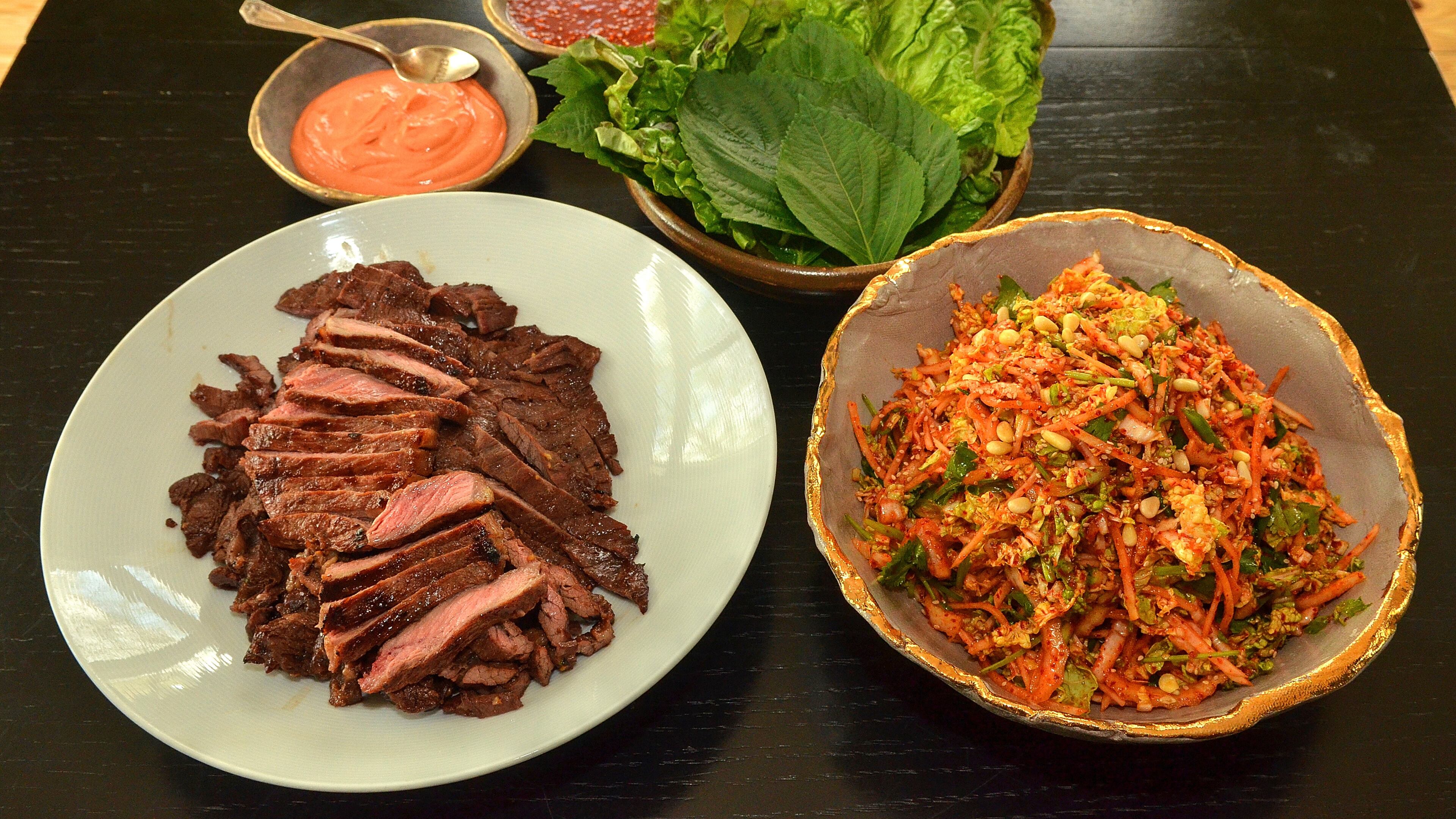 Soy-based marinated beef, Kimchi Slaw and sauces: Gochujang Sour Cream (orange sauce) and Ssamjang with romaine and perilla leaves await assembly. (Photo by Chris Hunt/Special)