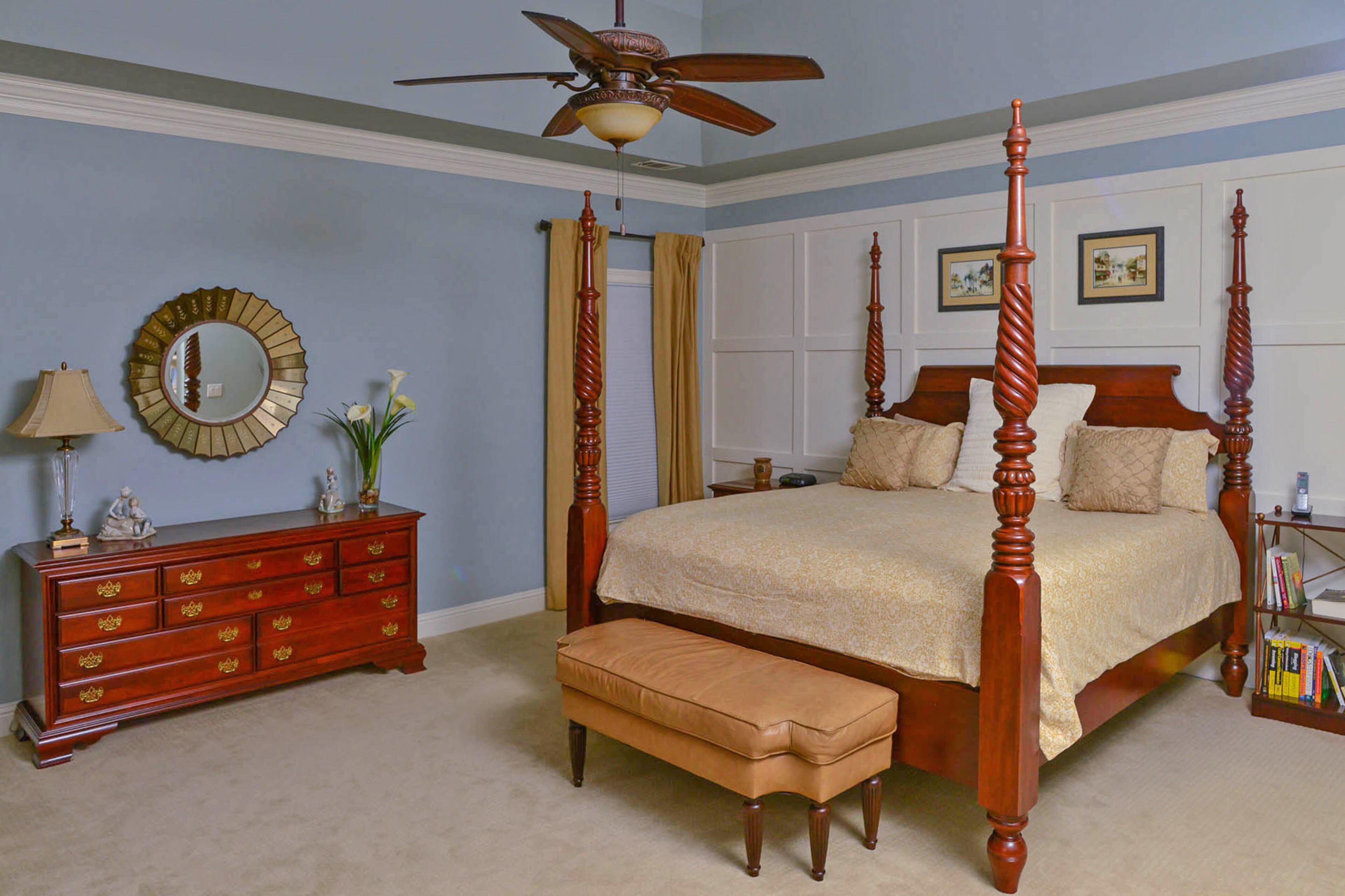A traditional wooden four-poster bed contrasts with the white paneled grid that serves as an accent wall. The paneling, which cost about $750, is among about $41,000 in renovations. The bedroom furniture is from Bassett, the custom window treatments are by Lori Harbrecht, and the walls are painted Sherwin-Williams Silvermist.