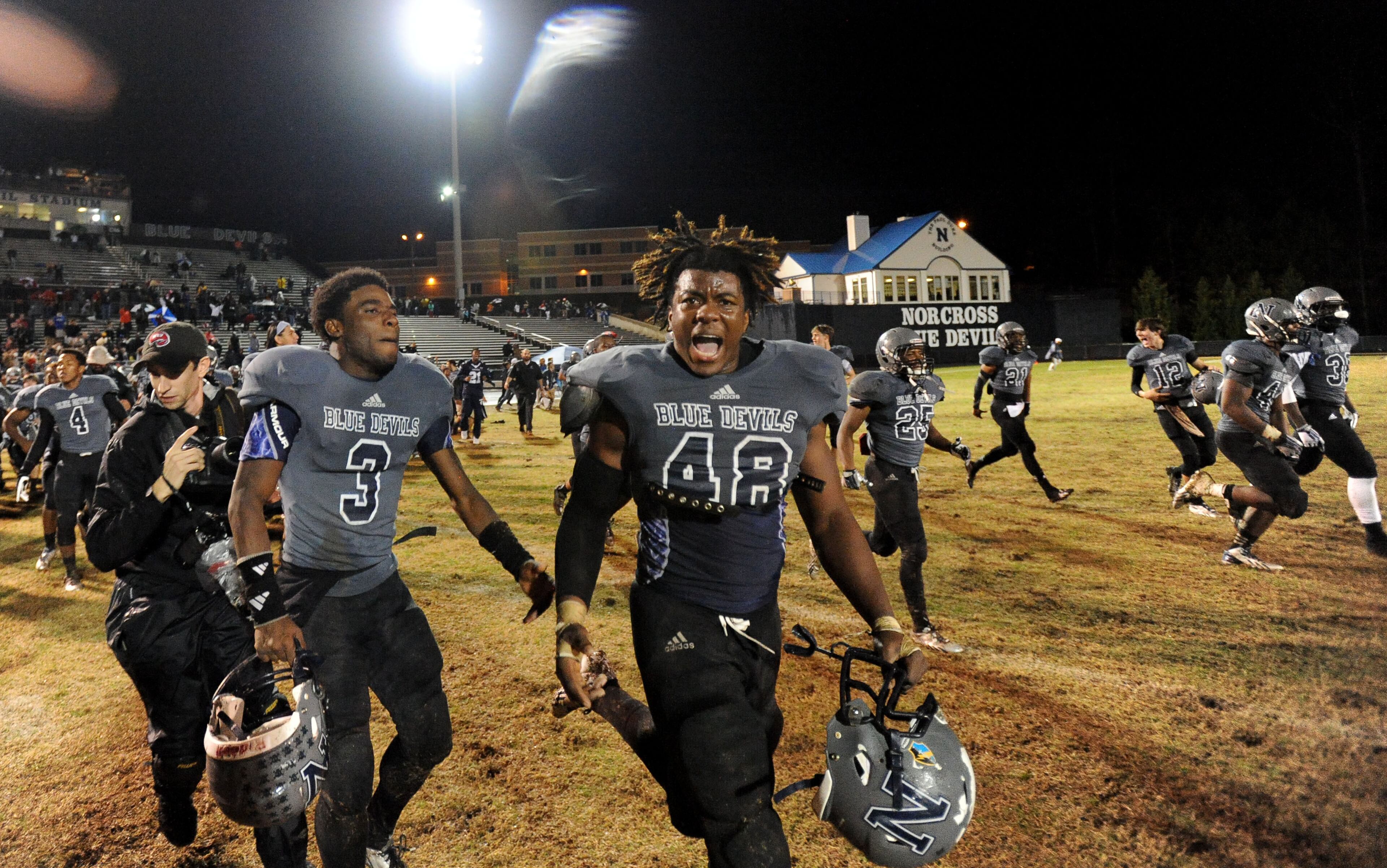 Norcross linebacker Kevin Mouhon (48) and defensive back Kentavius Latham (3) lead the celebrating Blue Devils onto the field as time runs out in their 14-9 AAAAAA win over Colquitt County on Friday, Dec. 6, 2013, in Norcross, Ga.
