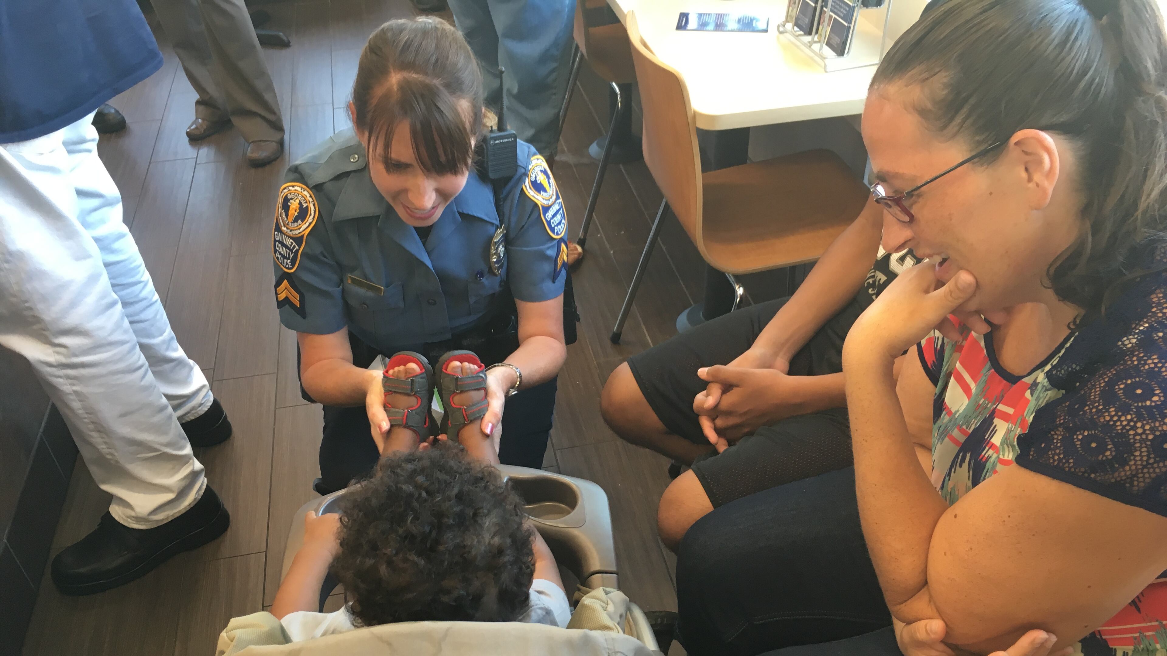 Gwinnett County police Cpl. Michele Pihera plays with a child Tuesday morning at a Dunkin' Donuts in Dacula while the boy's mom, Kylee Fulton, looks on. TYLER ESTEP/ TYLER.ESTEP@COXINC.COM