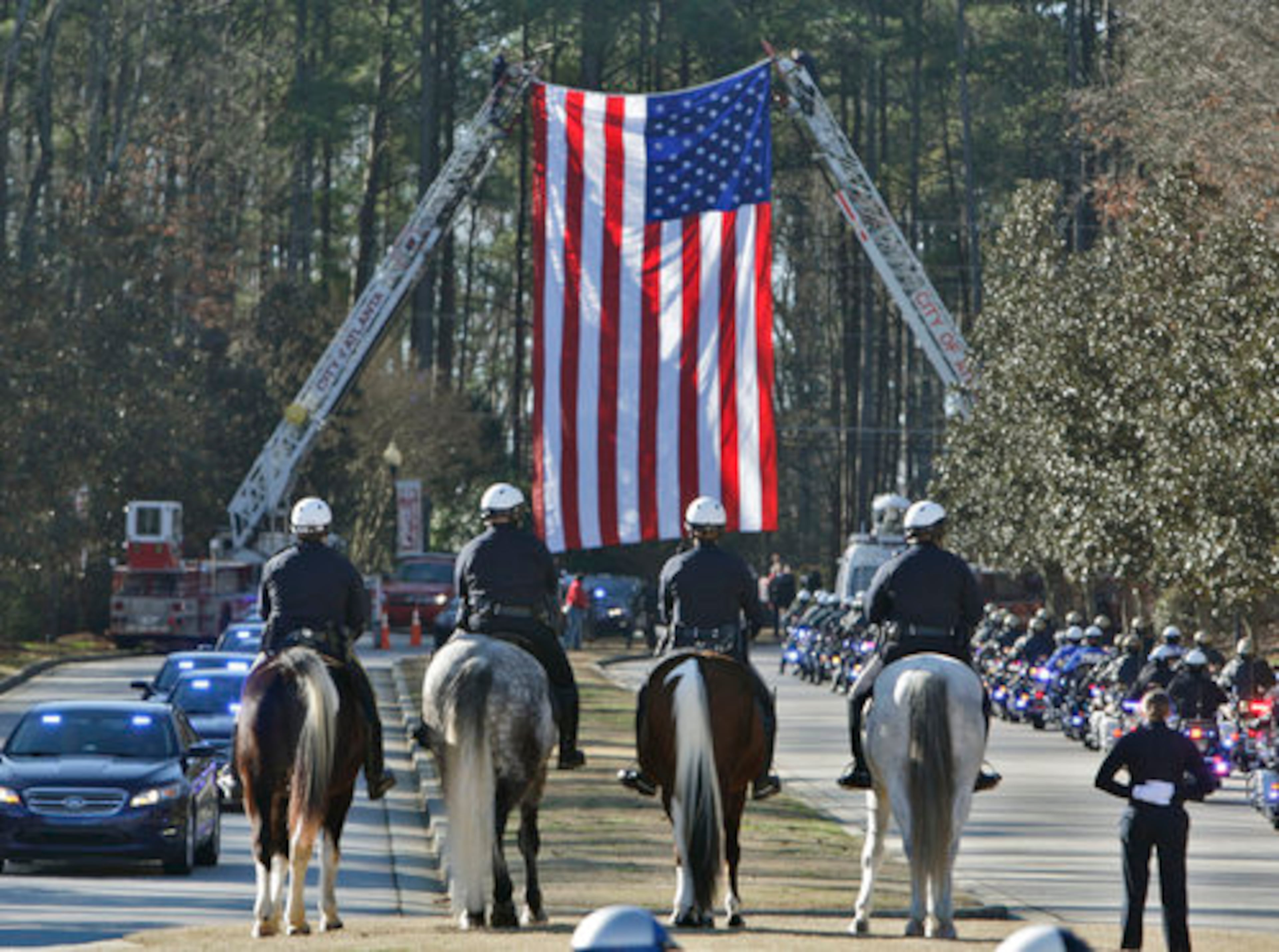 A police procession led by motorcycle patrol entered the church grounds beneath a giant American flag suspended by fire ladder trucks, and police units from throughout the area processed into the church.