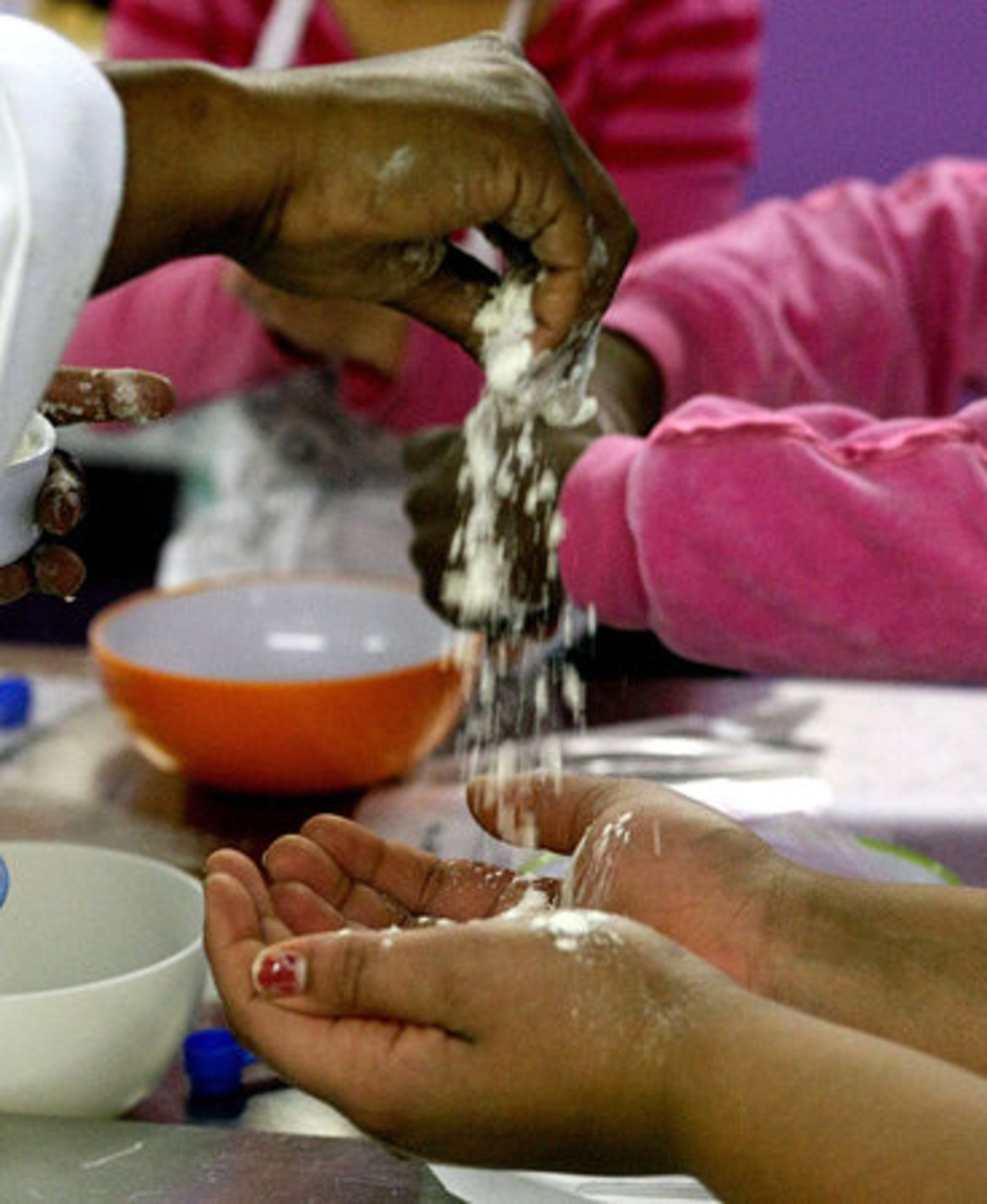 Instructor Dene Lynn sprinkles flour on a students hands. At Young Chefs Academy, culinary contenders from kindergarten through high school can apron up and hone their chops on cooking everything from maple cream tarts to egg foo yung.