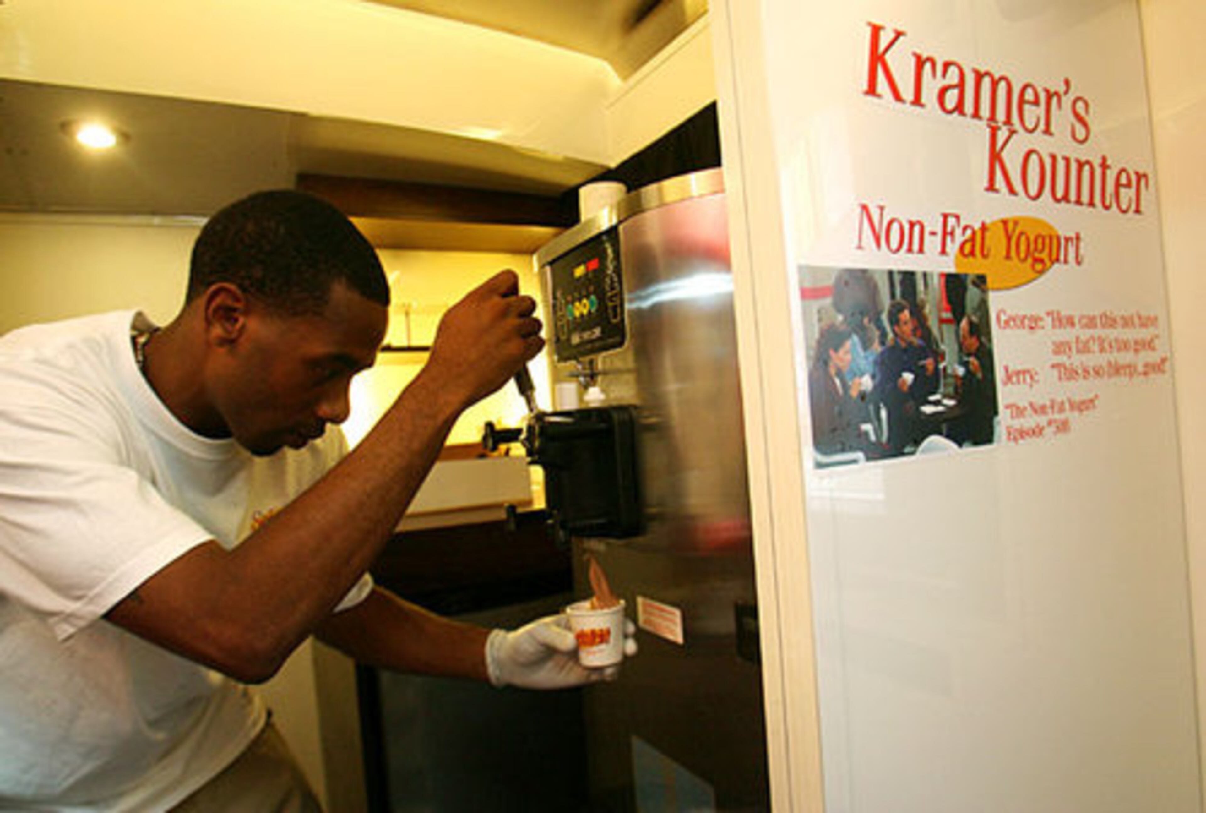 Employee Guy Walton serves up chocolate frozen yogurt to guests visiting the Seinfeld bus, filled with memoribilia and games. The frozen yogurt is a reference to the "Non-Fat Yogurt" episode of Seinfeld.