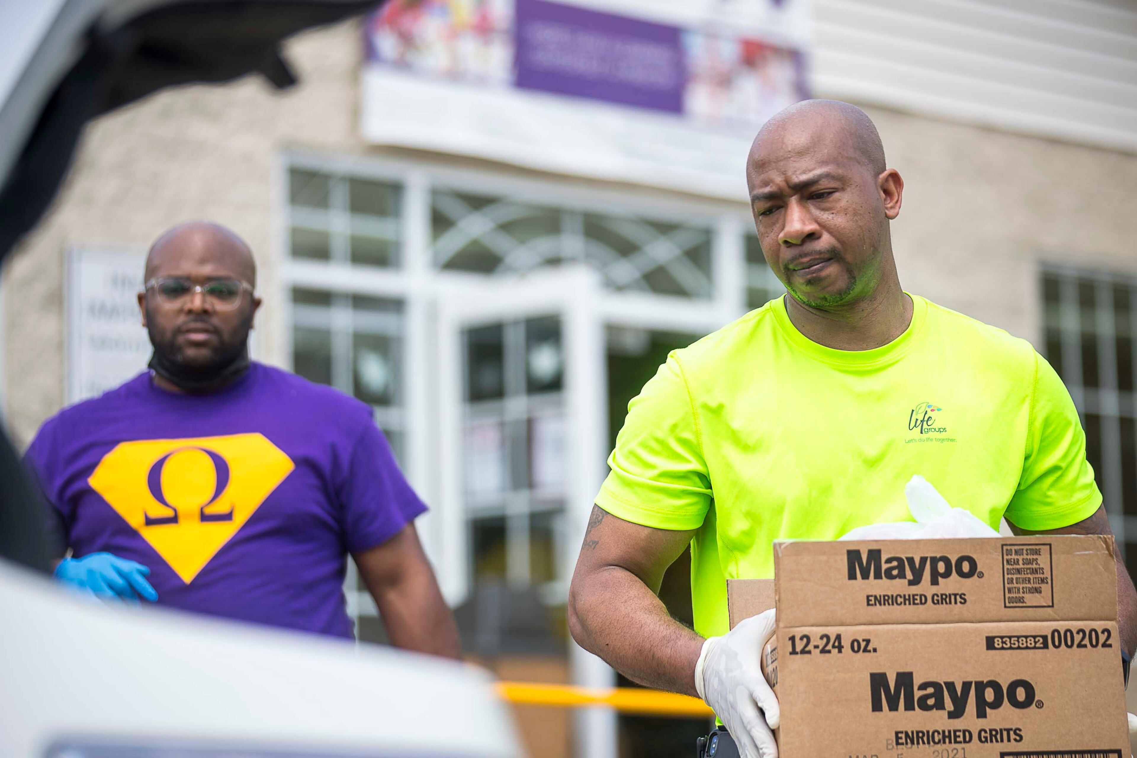 04/09/2020 - Atlanta, Georgia - Elizabeth Baptist Church members Dimitri Yates (left) and Johnny Smith (right) give a family in need boxes of groceries and toiletries during an Atlanta Community Food Bank and Fulton County Schools collaborative distribution at Elizabeth Baptist Church in Atlanta, Thursday, April 9, 2020. (ALYSSA POINTER / ALYSSA.POINTER@AJC.COM)