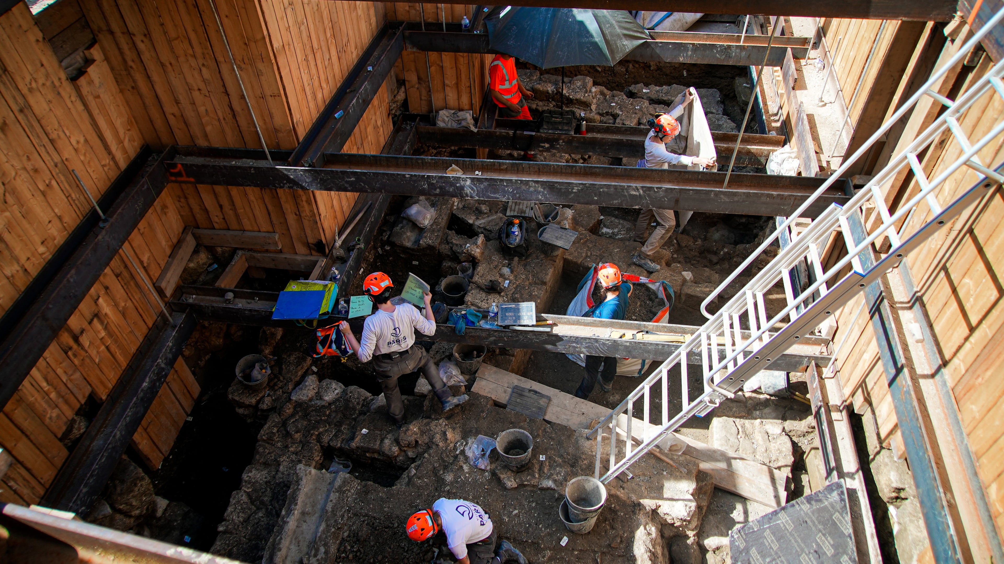 Archaeological workers wearing hard hats dig 4 meters (13 feet) underground during excavations outside Notre-Dame Cathedral in Paris, Monday, June 1, 2026. (AP Photo/Nicolas Garriga)