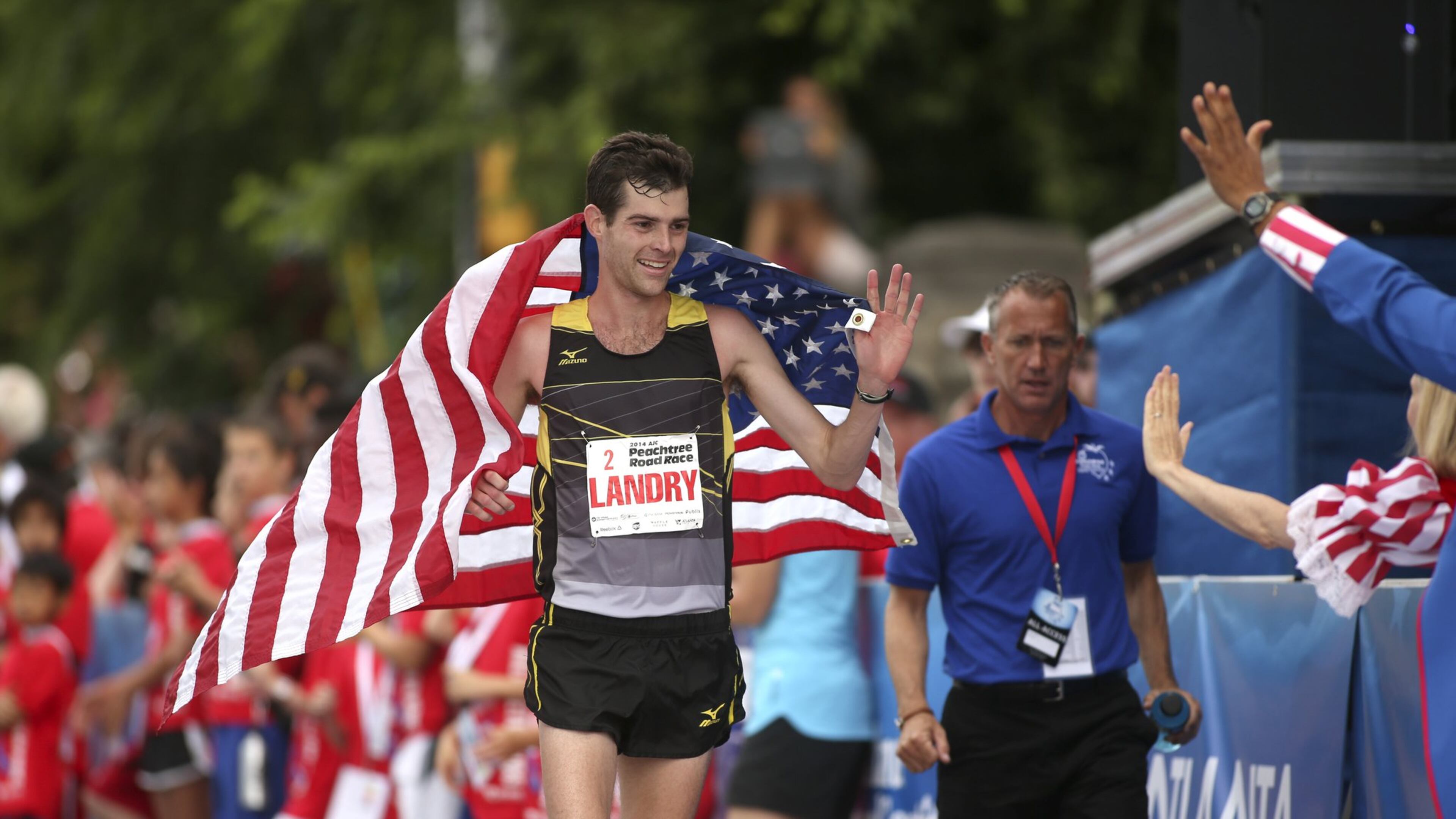 Christo Landry celebrates with fans after winning the men’s field of the 2014 AJC Peachtree Road Race. PHOTO BY / JASON GETZ