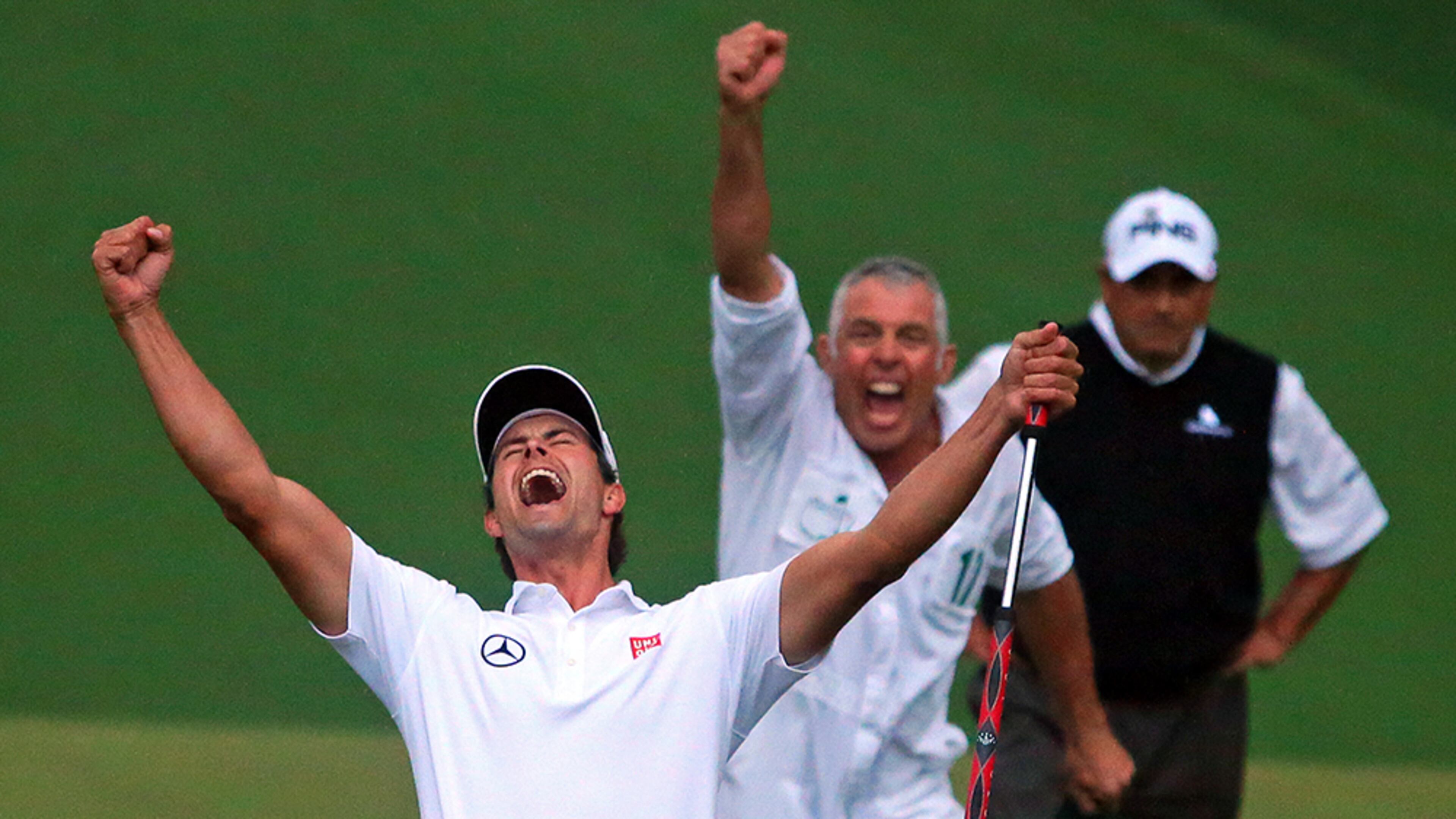 With runner-up Angel Cabrera looking on (background), Adam Scott and his caddy, Steve Williams (center), celebrate the putt dropping on the second playoff hole on the 10th green to win the Masters Tournament at Augusta National Golf Club.