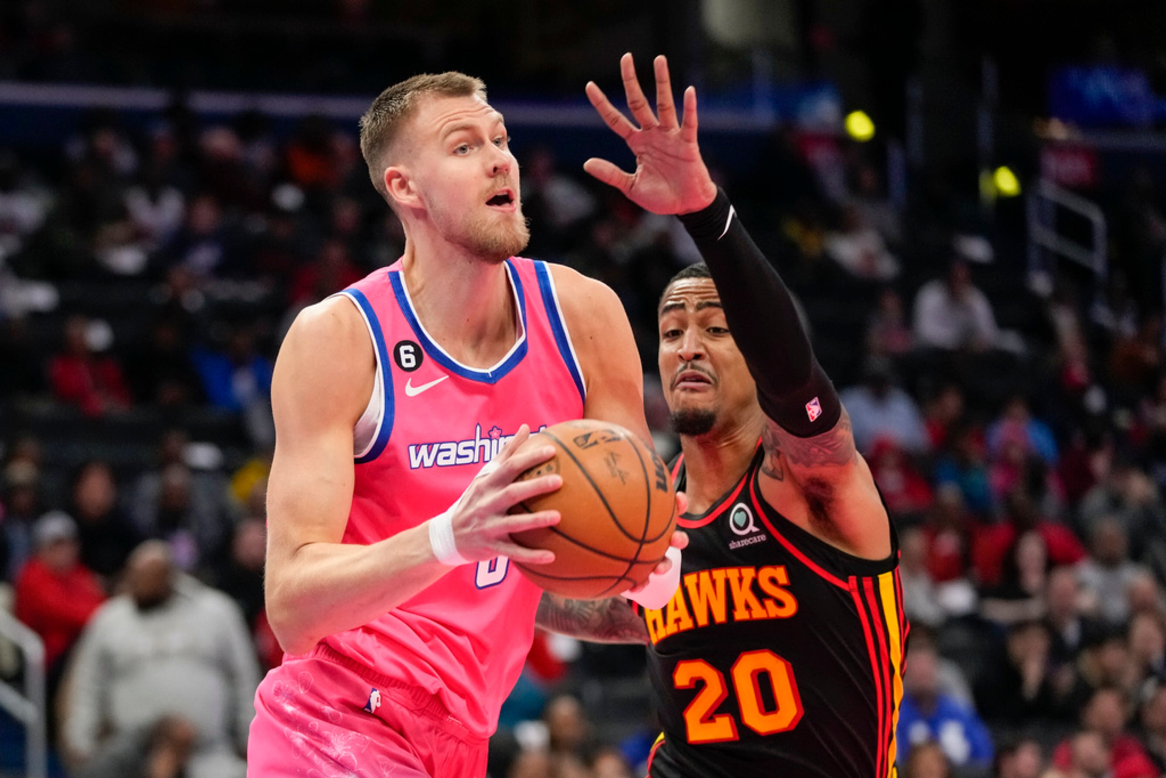 Washington Wizards center Kristaps Porzingis, left, looks to pass in front of Atlanta Hawks forward John Collins during the first half of an NBA basketball game Wednesday, March 8, 2023, in Washington. (AP Photo/Alex Brandon)