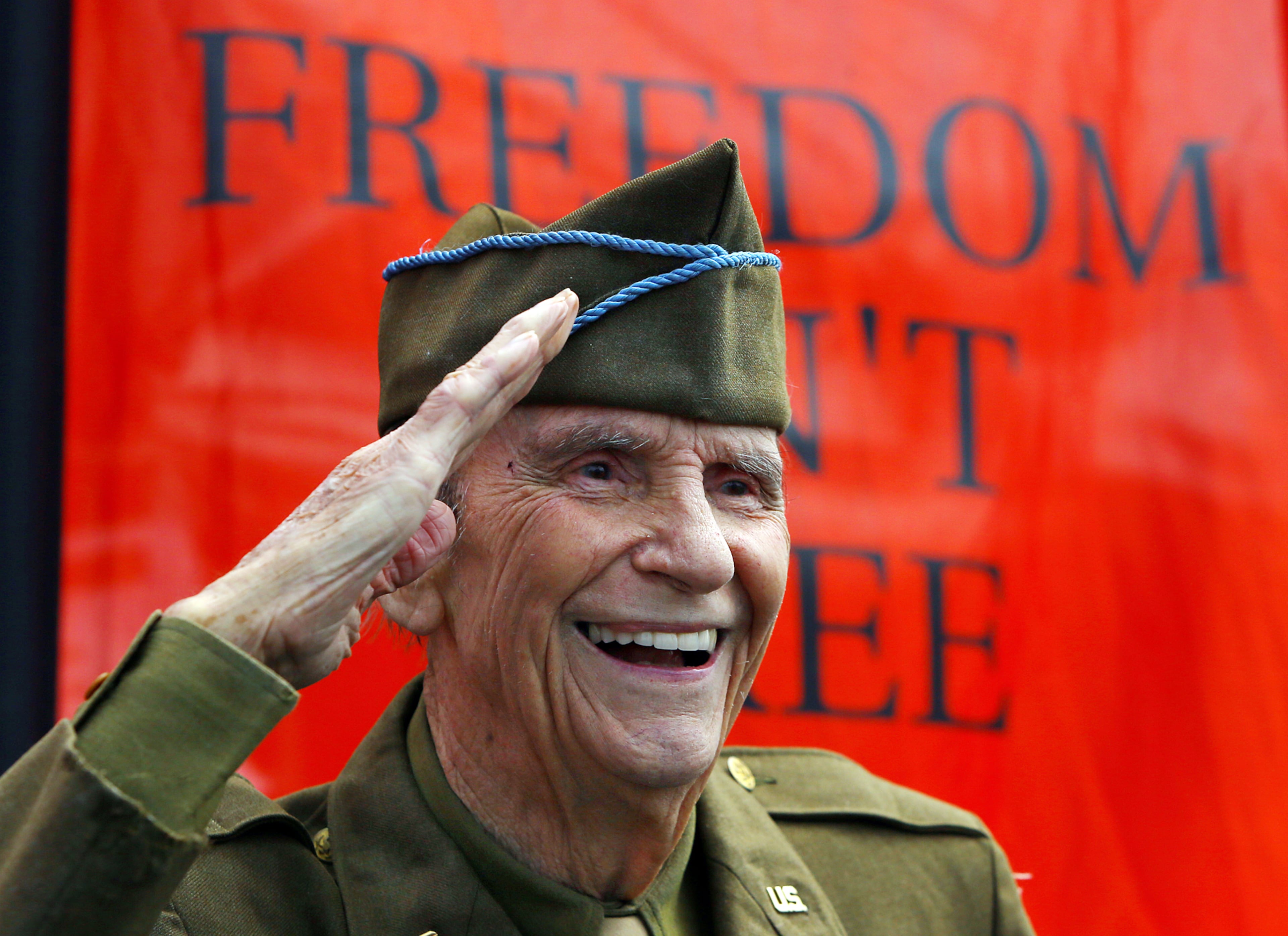 WWII veteran Bud Sosebee, 89, salutes passing onlookers snapping photos at the fundraiser to benefit the Walk of Heroes booth at the 33rd Annual Conyers Cherry Blossom Festival on Sunday, March 23, 2014, in Conyers.