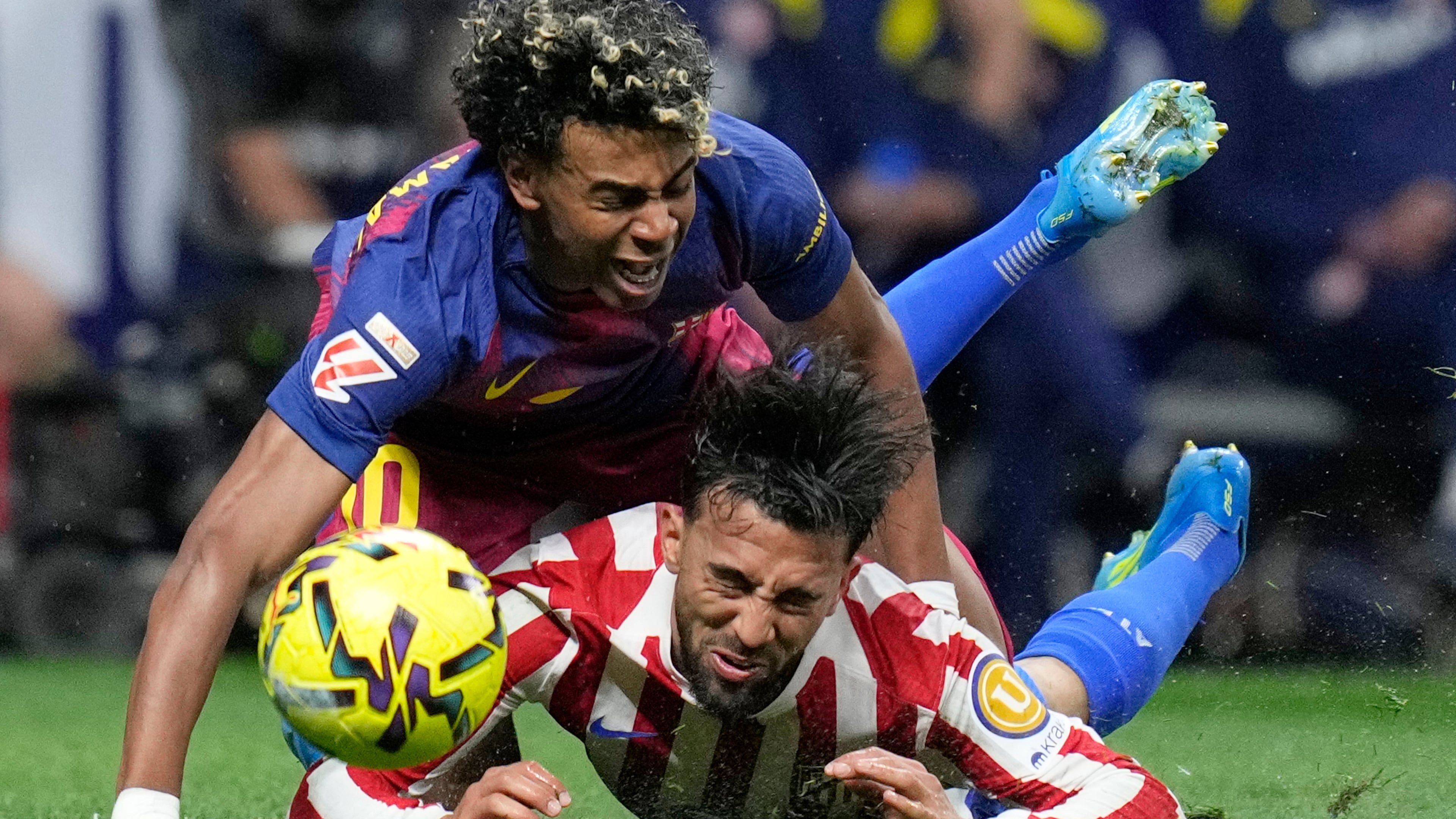 Barcelona's Lamine Yamal, top, is tackled and fouled by Atletico Madrid's Nico Gonzalez, who receives a second yellow card and is then sent off during a La Liga soccer match between Atletico Madrid and Barcelona in Madrid, Spain, Saturday, April 4, 2026. (AP Photo/Bernat Armangue)