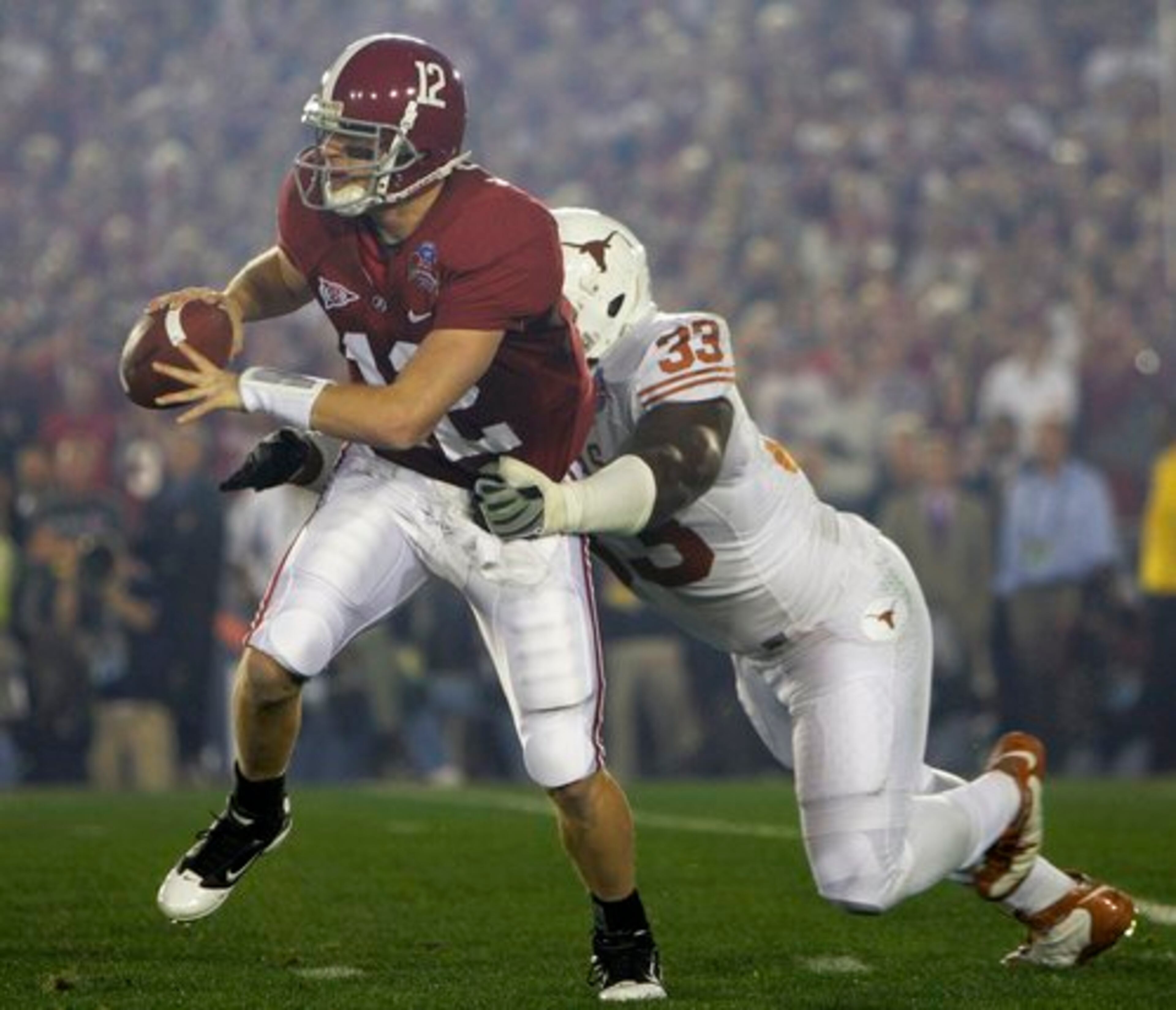 Alabama quarterback Greg McElroy is pressured by Texas defensive tackle Lamarr Houston (33).