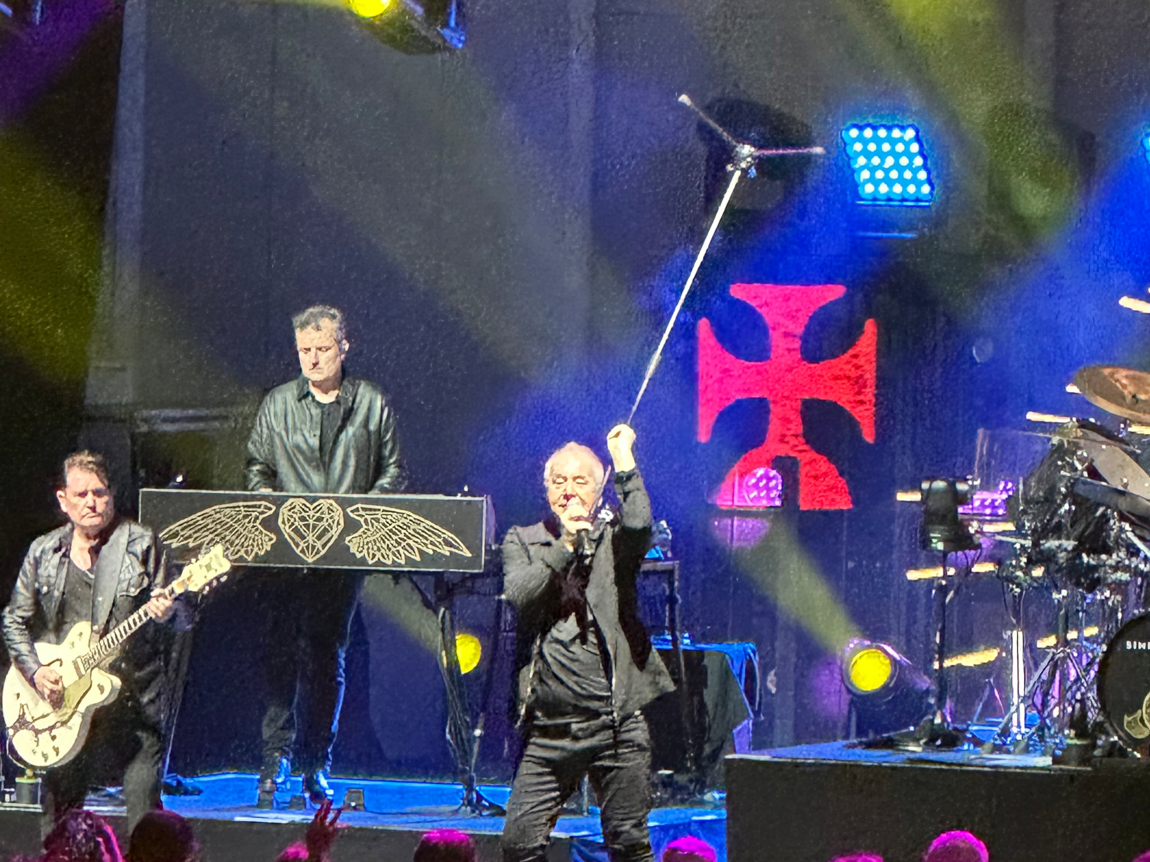 Jim Kerr of Simple Minds twirls his mic stand during the band's appearance at a nearly sold-out Synovus Bank Amphitheater at Chastain Park on Saturday. (Rodney Ho/AJC)