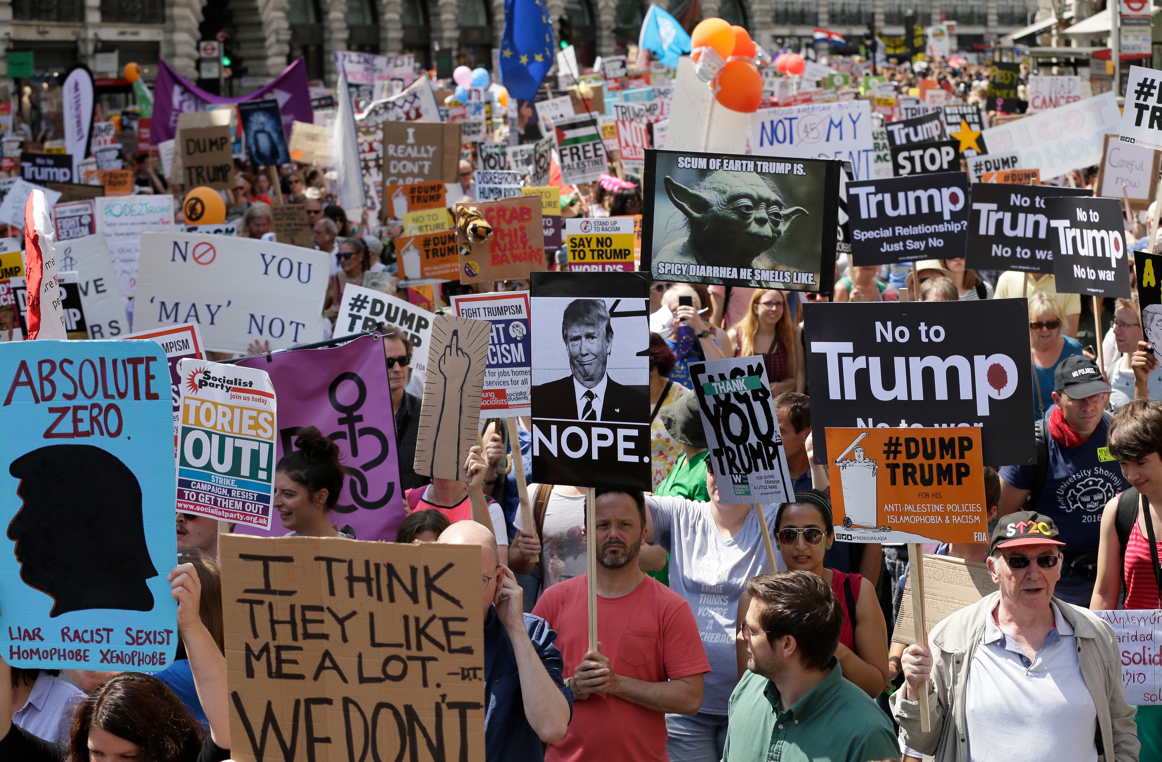Protestors hold banners during a march opposed to the visit of U.S. President Donald Trump in London, Friday, July 13, 2018. Trump's pomp-filled welcome to Britain was overshadowed Friday by an explosive interview in which he blasted Prime Minister Theresa May, blamed London's mayor for terror attacks against the city and argued that Europe was "losing its culture" because of immigration. (AP Photo/Tim Ireland)