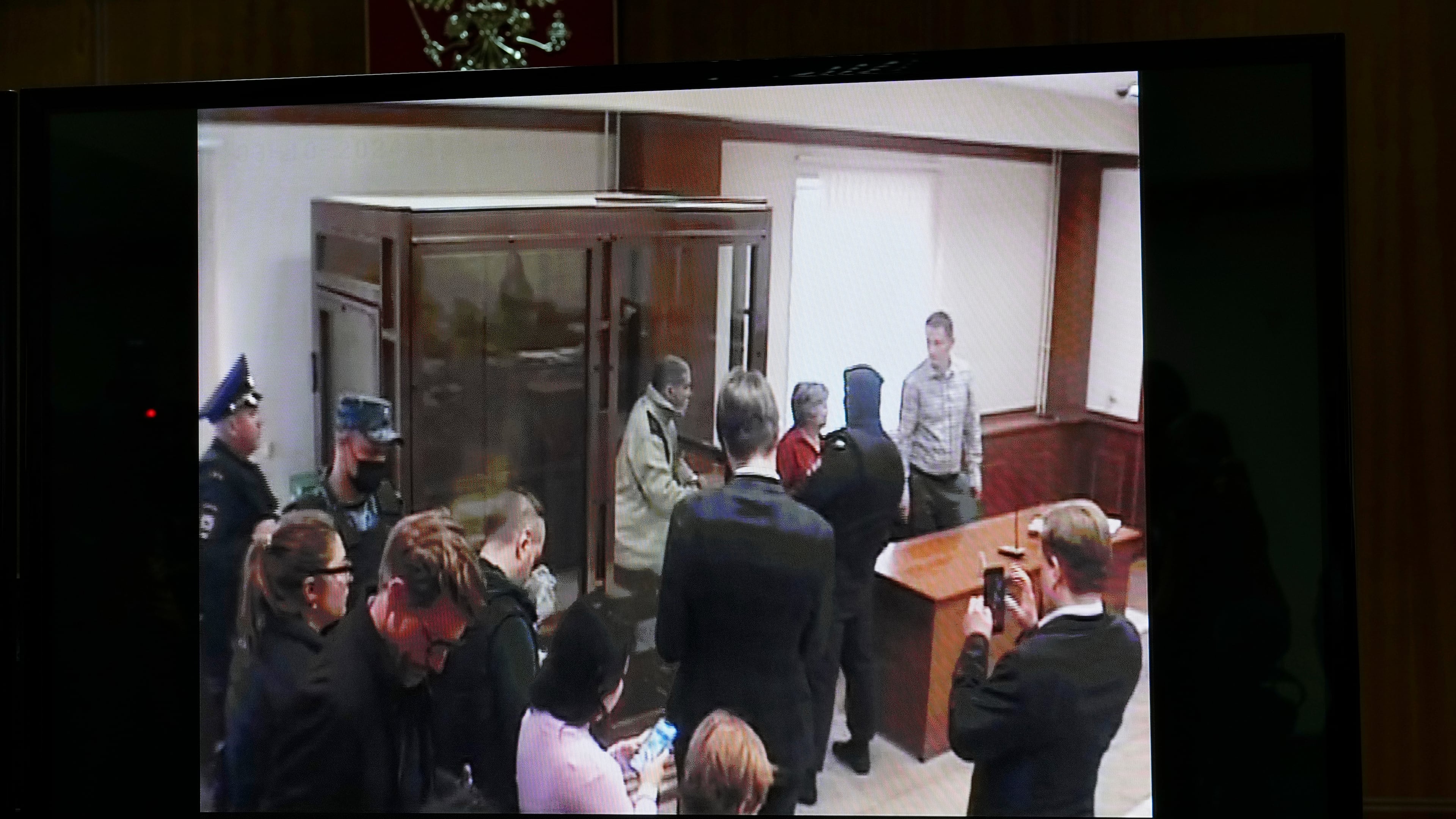 FILE - Stephen Hubbard, a U.S. citizen accused of fighting as a mercenary in Ukraine against Russia shows up in a video link as he stands in a glass cage during a court session in the Moscow City court in Moscow, Russia, Monday, Oct. 7, 2024. (AP Photo/Alexander Zemlianichenko, File)
