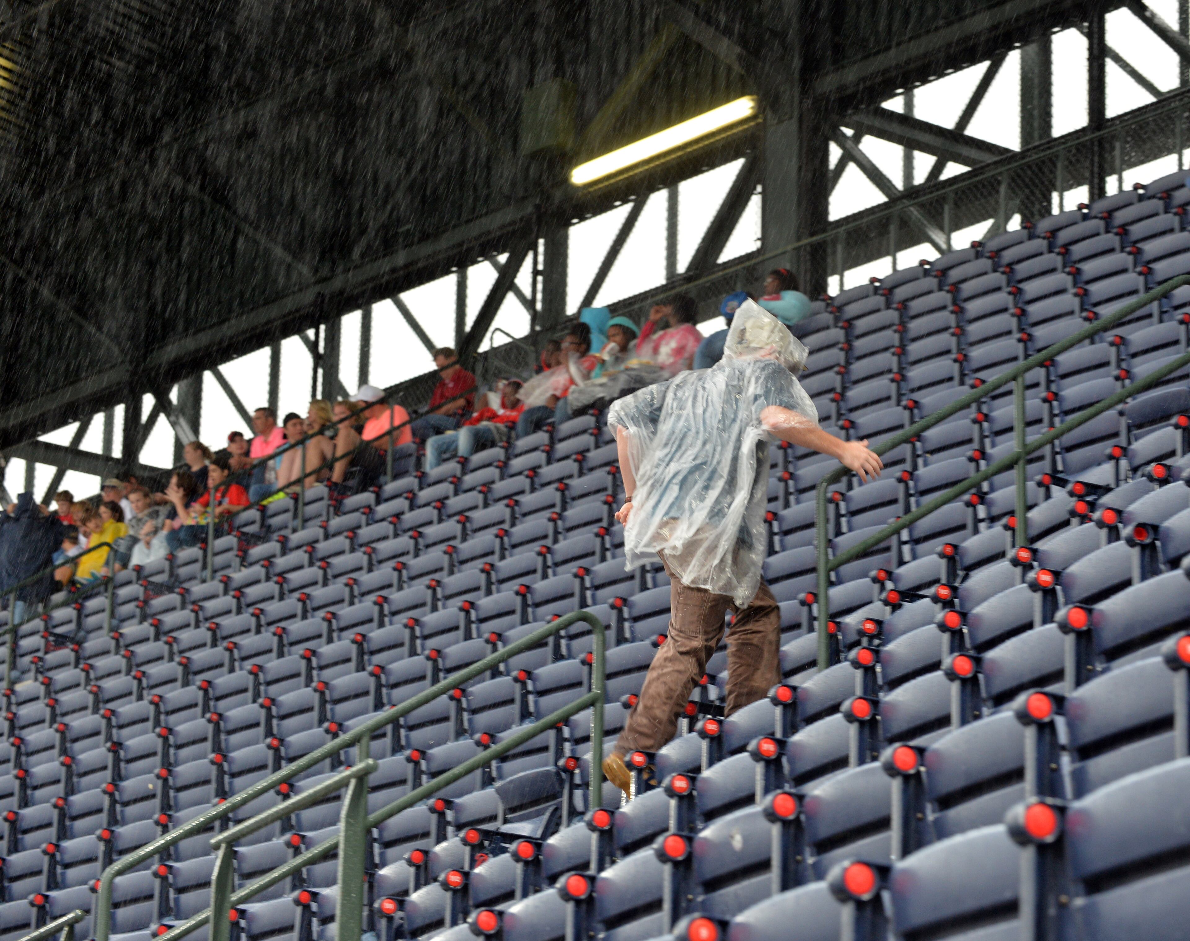 A fans runs for shelter from the rain before the start of the Atlanta Braves game at Turner Field Friday May 9, 2014. The Braves are scheduled to play the Chicago Cubs tonight at 7:35pm. BRANT SANDERLIN /BSANDERLIN@AJC.COM