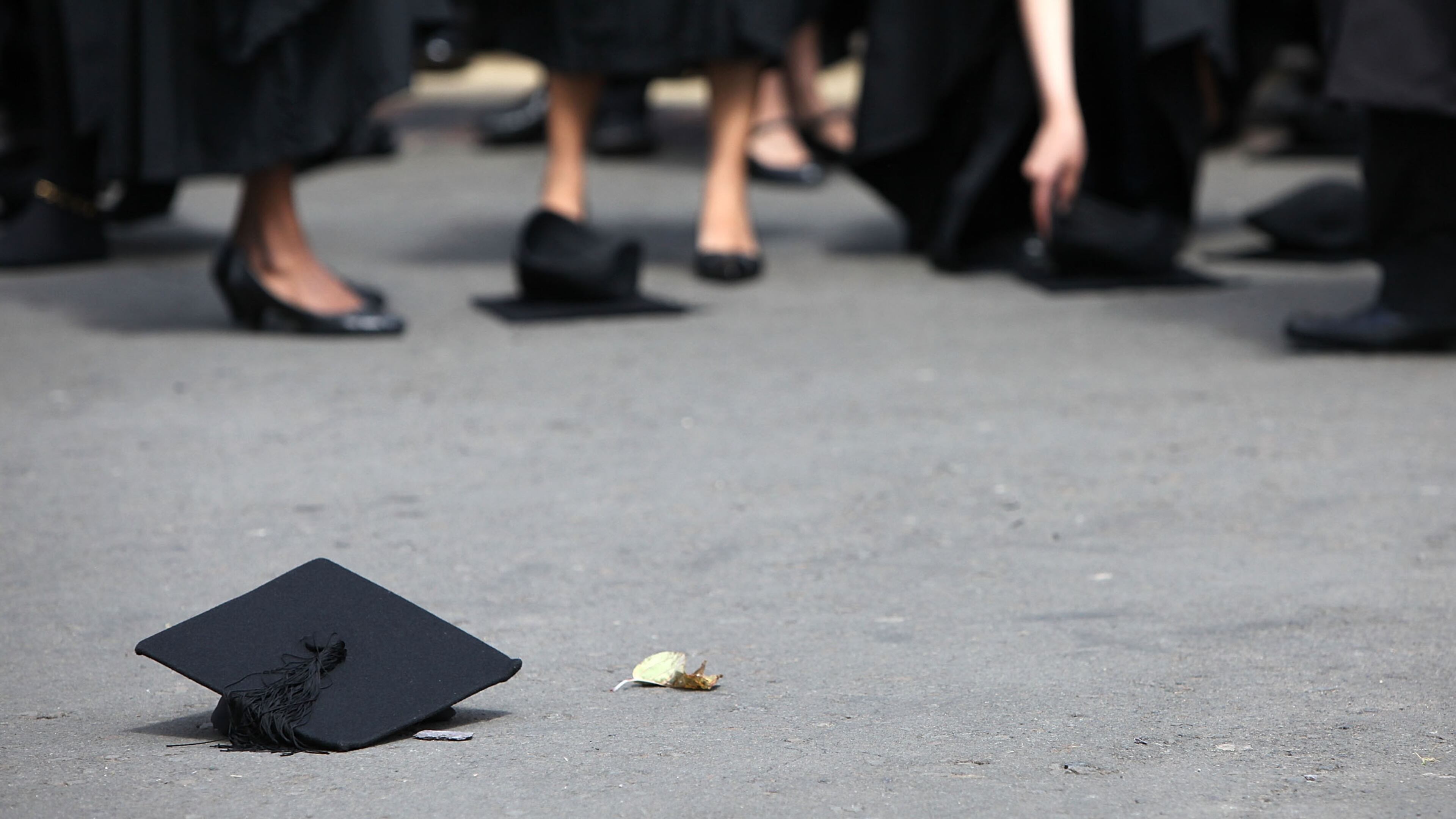 Students pick up their mortarboards after the official hat throwing photograph. (Photo: Christopher Furlong/Getty Images)