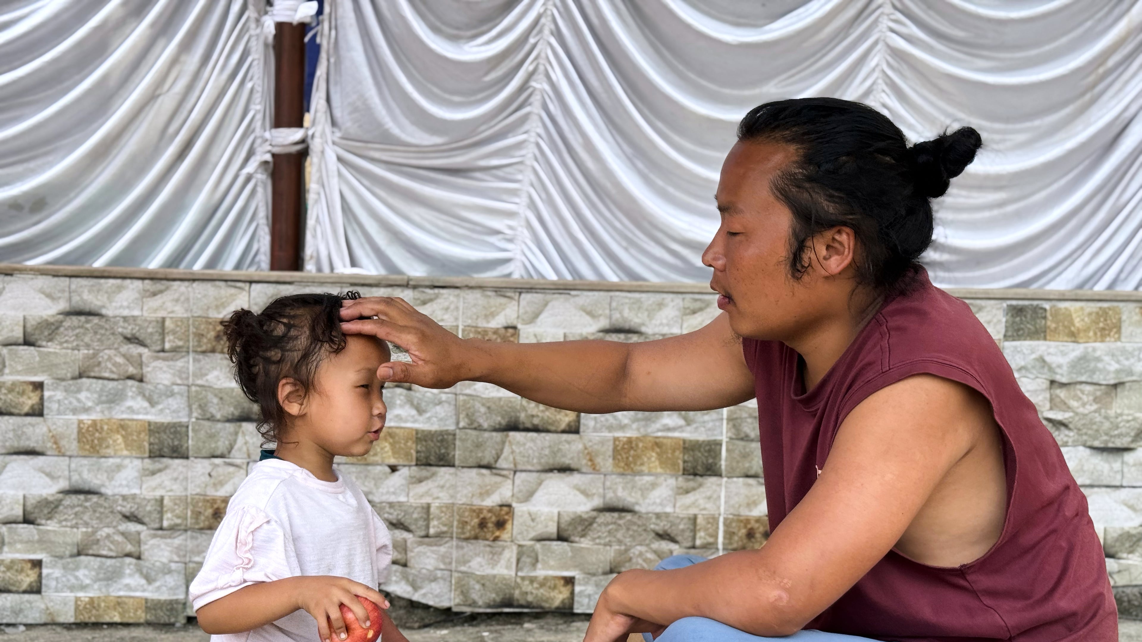 Survivor Tsering Gelbu Lama sits with his daughter at a monastery in Kathmandu, Nepal, Monday, Aug. 31, 2026. (AP Photo/Niranjan Shrestha)