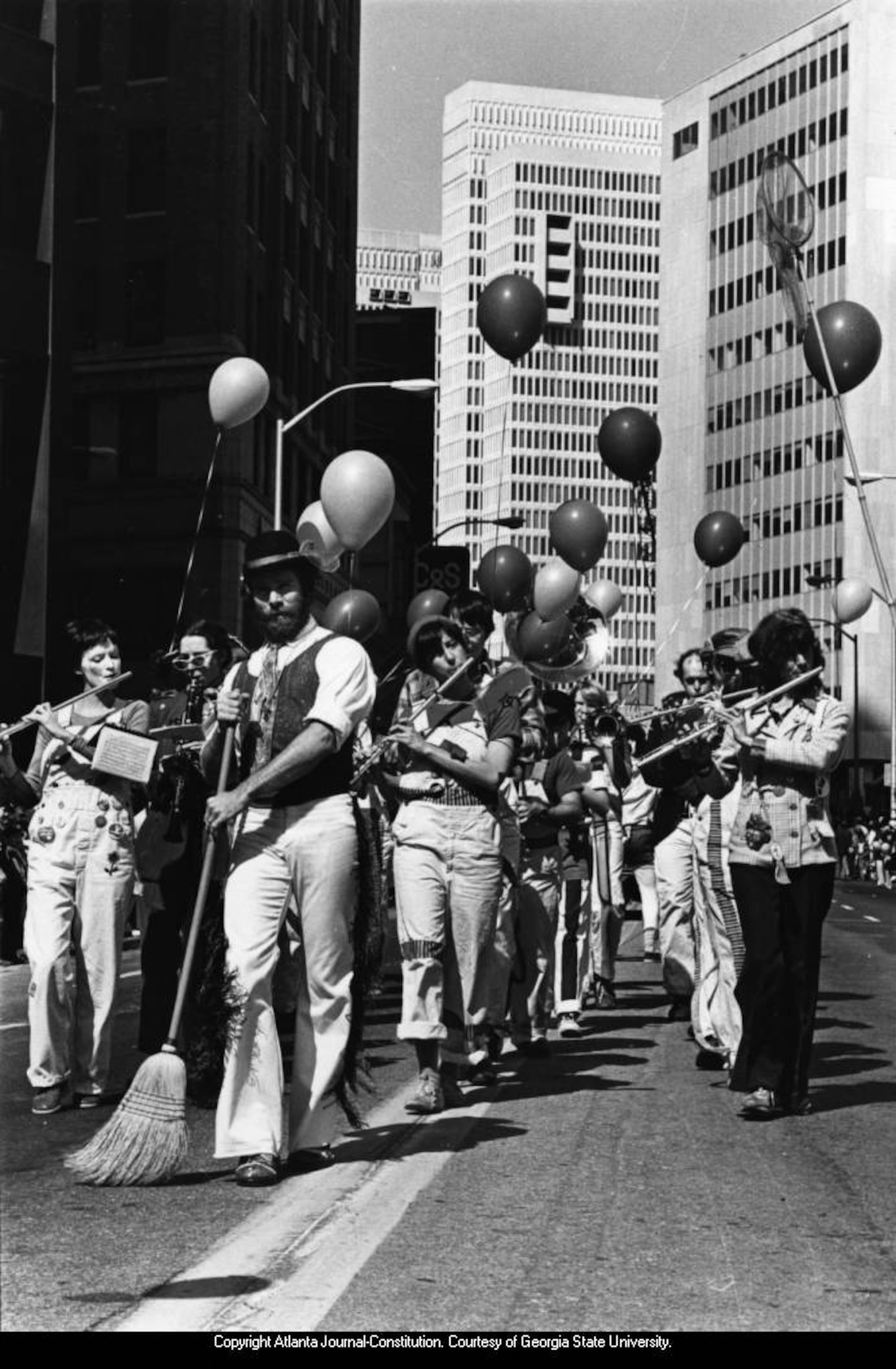 March 16, 1980 -- The original caption for this photo was "Wearin' the Green Again: A merry band of Irish folk does a little bit of cleanup on Peachtree Street Saturday as Atlantans get ready for St. Patrick's Day Monday. Better known around town as Kelley's Feed and Seed Marching Band, these entertainers, from flutists to broom pusher, were among the many groups marching in the weekend parade." JUDY ONDREY / AJC PHOTO ARCHIVES