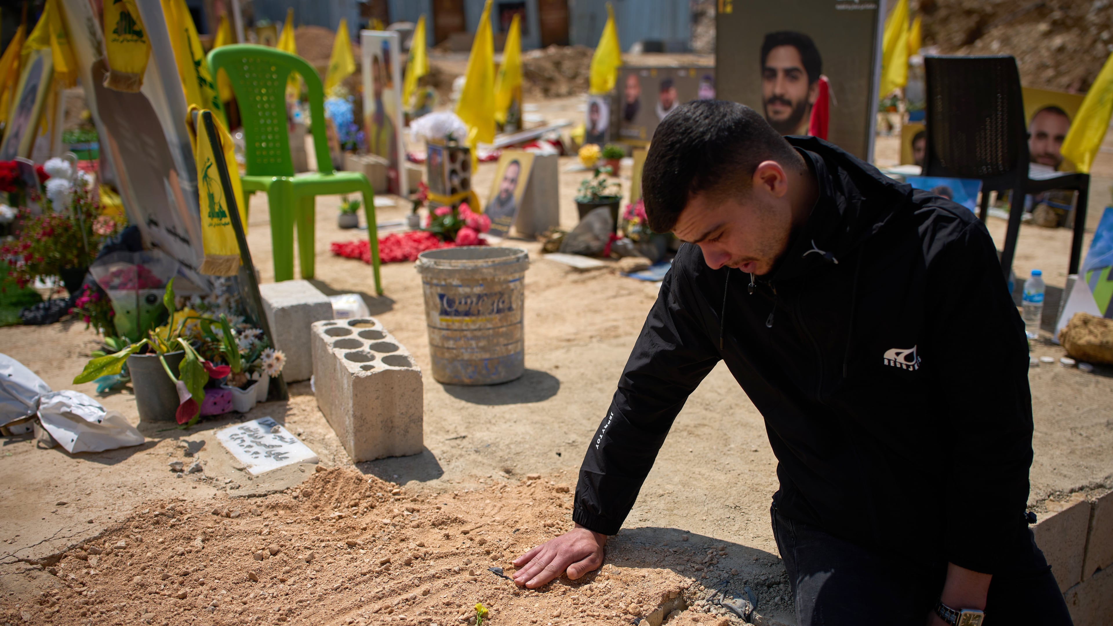 Ahmad Assi, 29, cries on the grave of his friend Hassan Ali Badawi, a paramedic of the Lebanese Red Cross killed in a Israeli strike, during his funeral in Choueifat, Lebanon, Monday, April 13, 2026. (AP Photo/Emilio Morenatti)